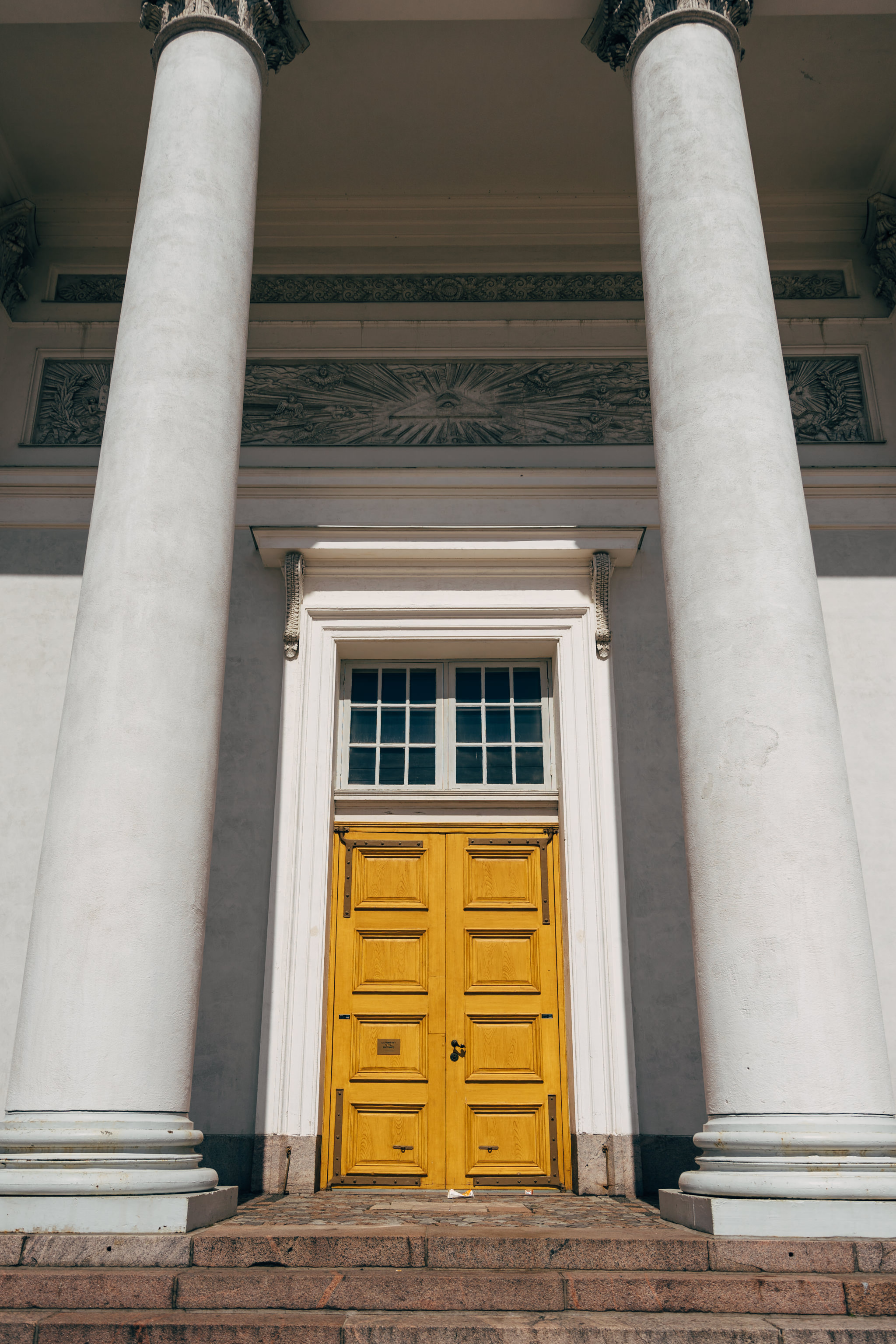 Helsinki Cathedral entrance with yellow doors flanked by white columns.