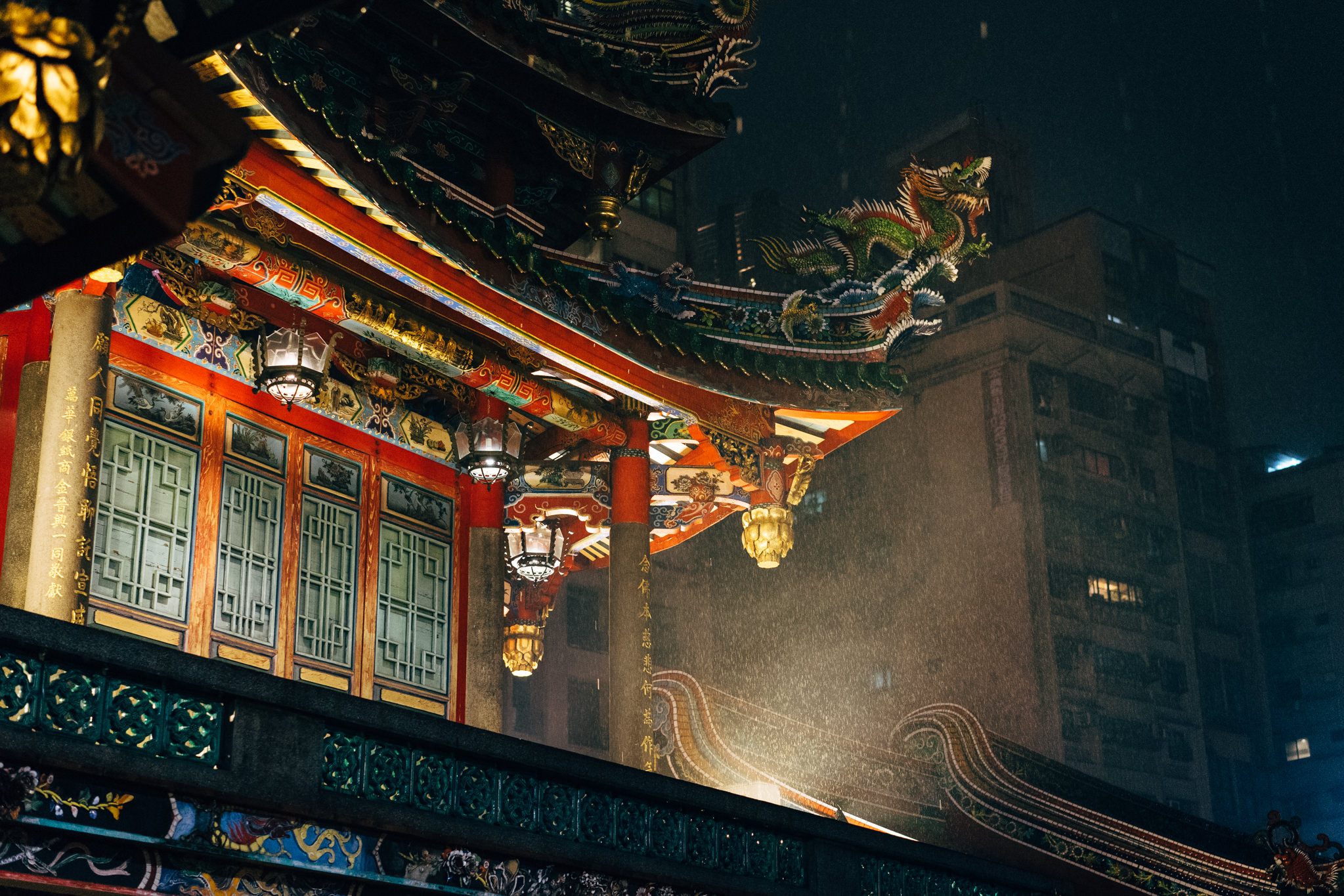 Nighttime view of ornate Longshan Temple in Taipei, Taiwan, rain falling.