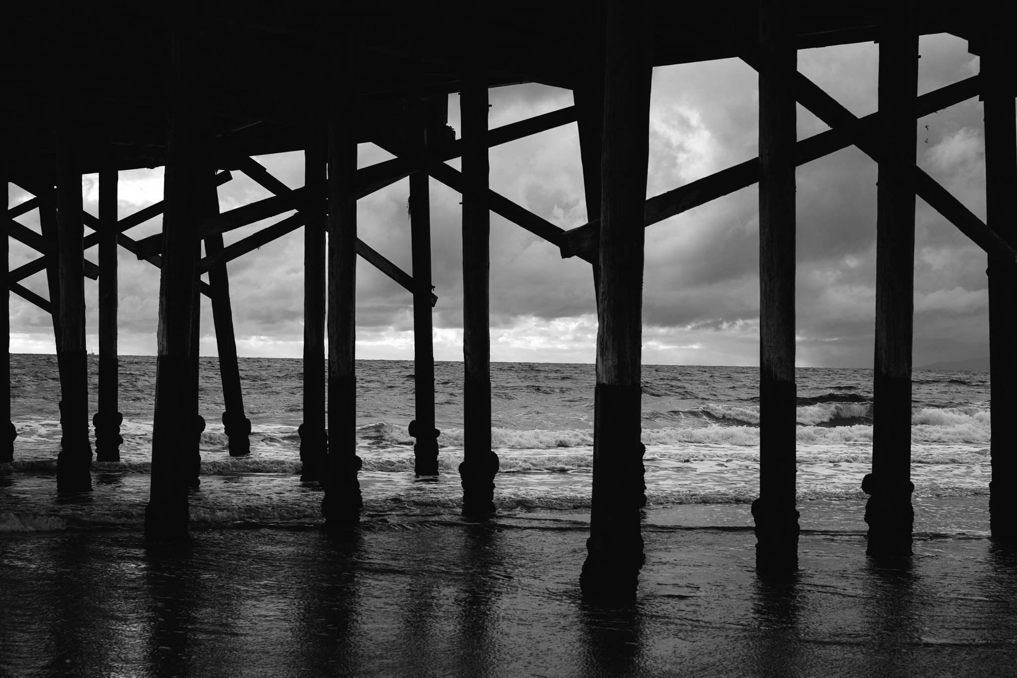 Black and white photo of a pier over the ocean.