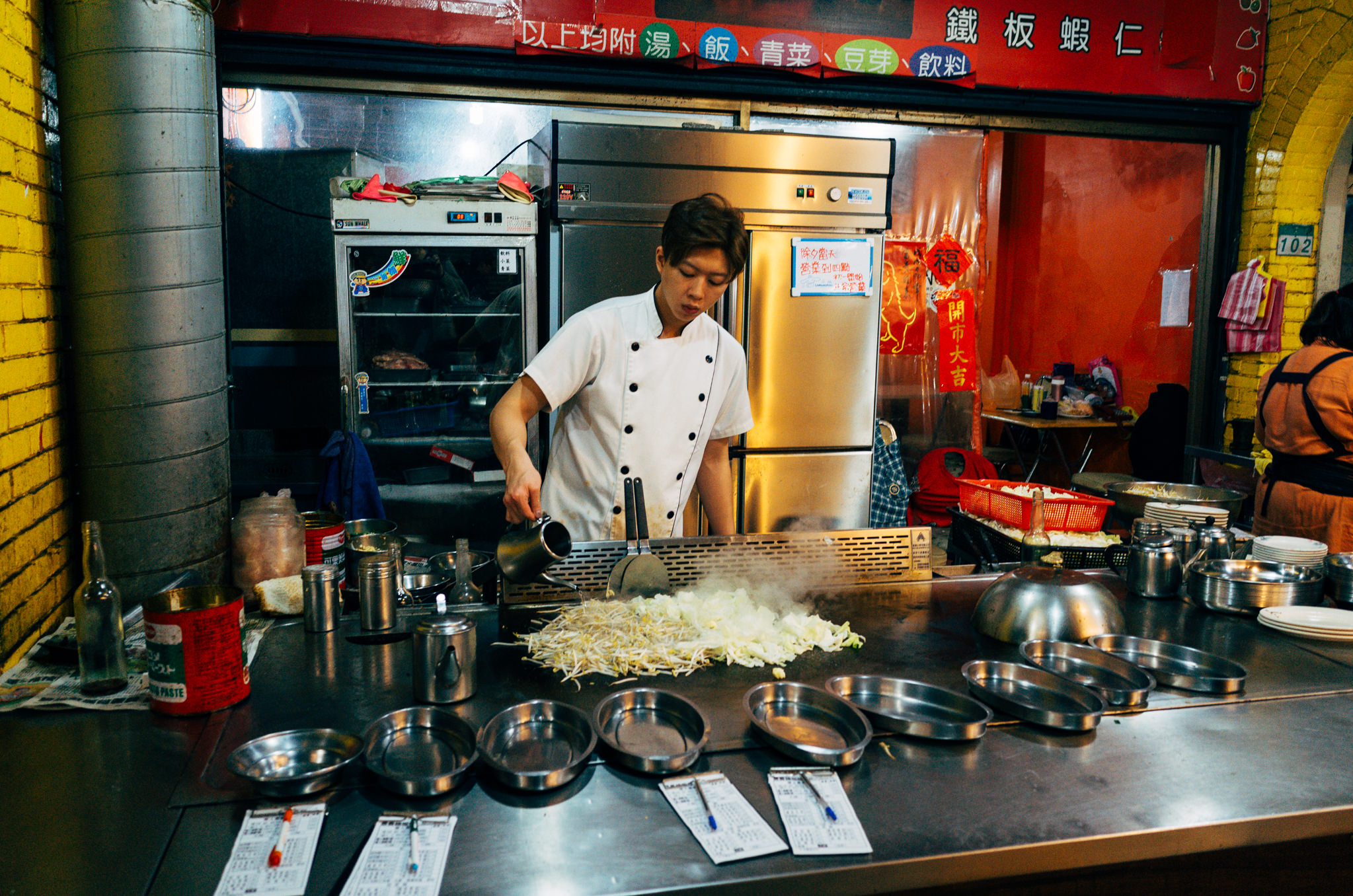 Chef preparing Taiwanese street food on a teppanyaki grill.