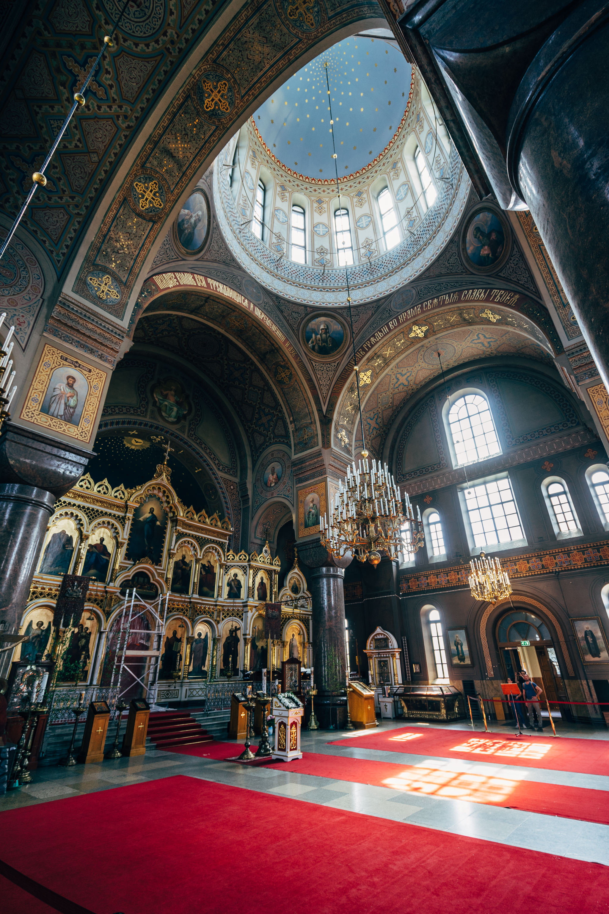 Interior of Uspenski Cathedral, Helsinki, featuring ornate architecture, iconostasis, and a red carpet.