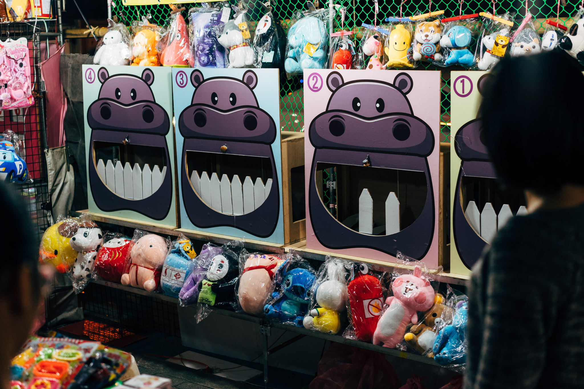 Four hippopotamus-shaped carnival game booths with stuffed animal prizes.