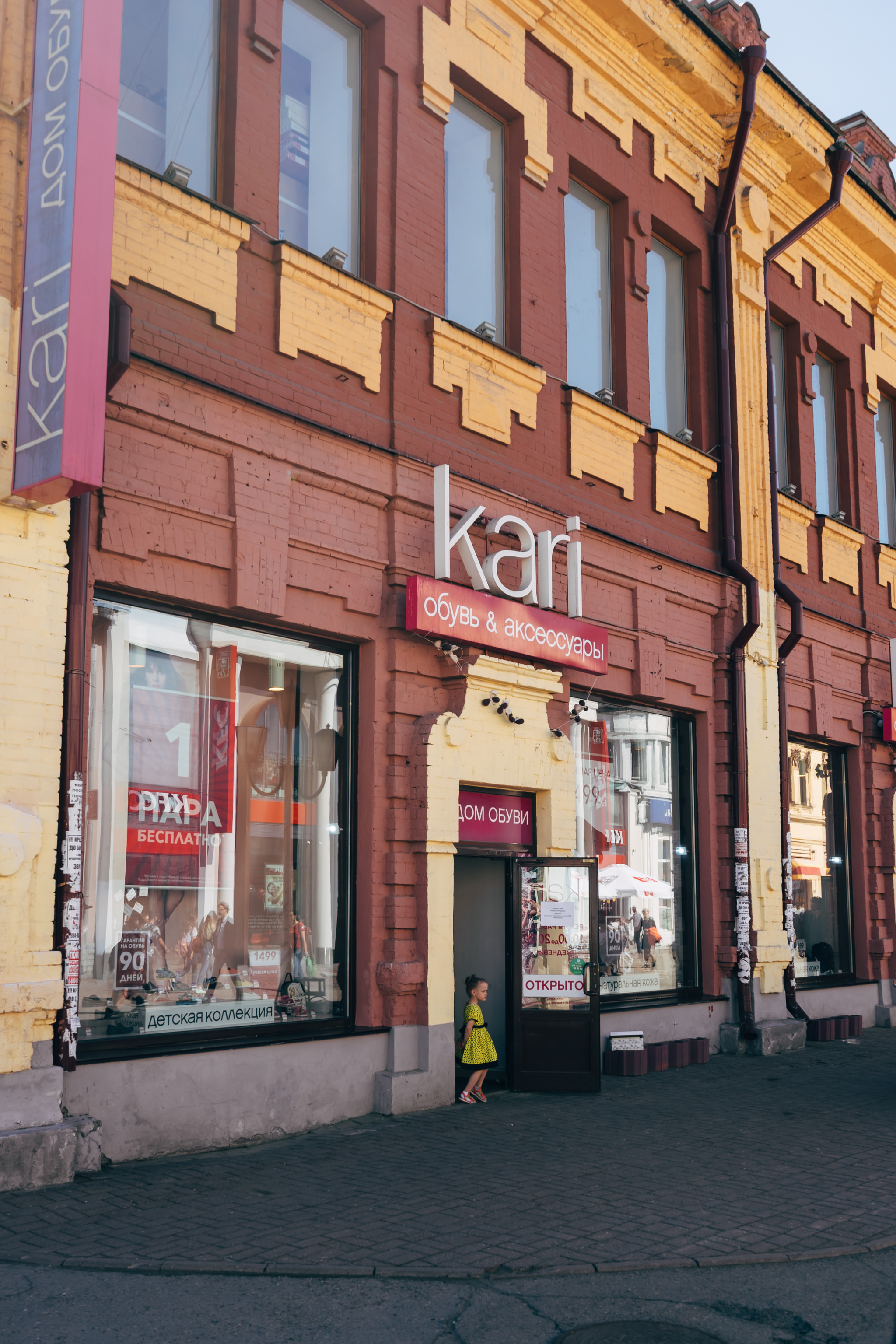 Girl in yellow polka dot dress standing outside Kari shoe store.
