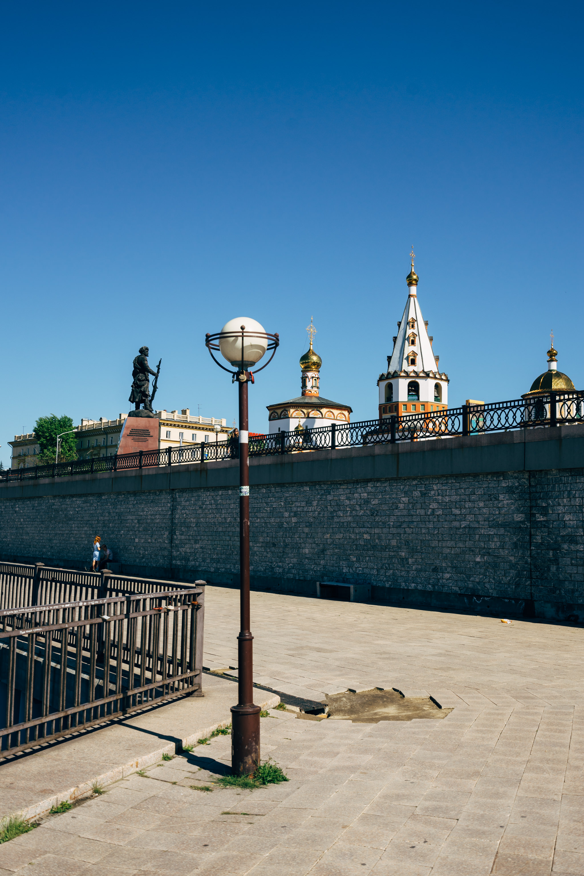 Siberian church and statue viewed from paved walkway.