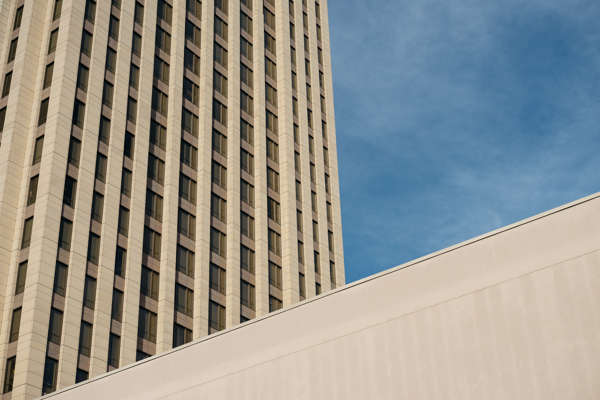 Tall beige building against a blue sky.