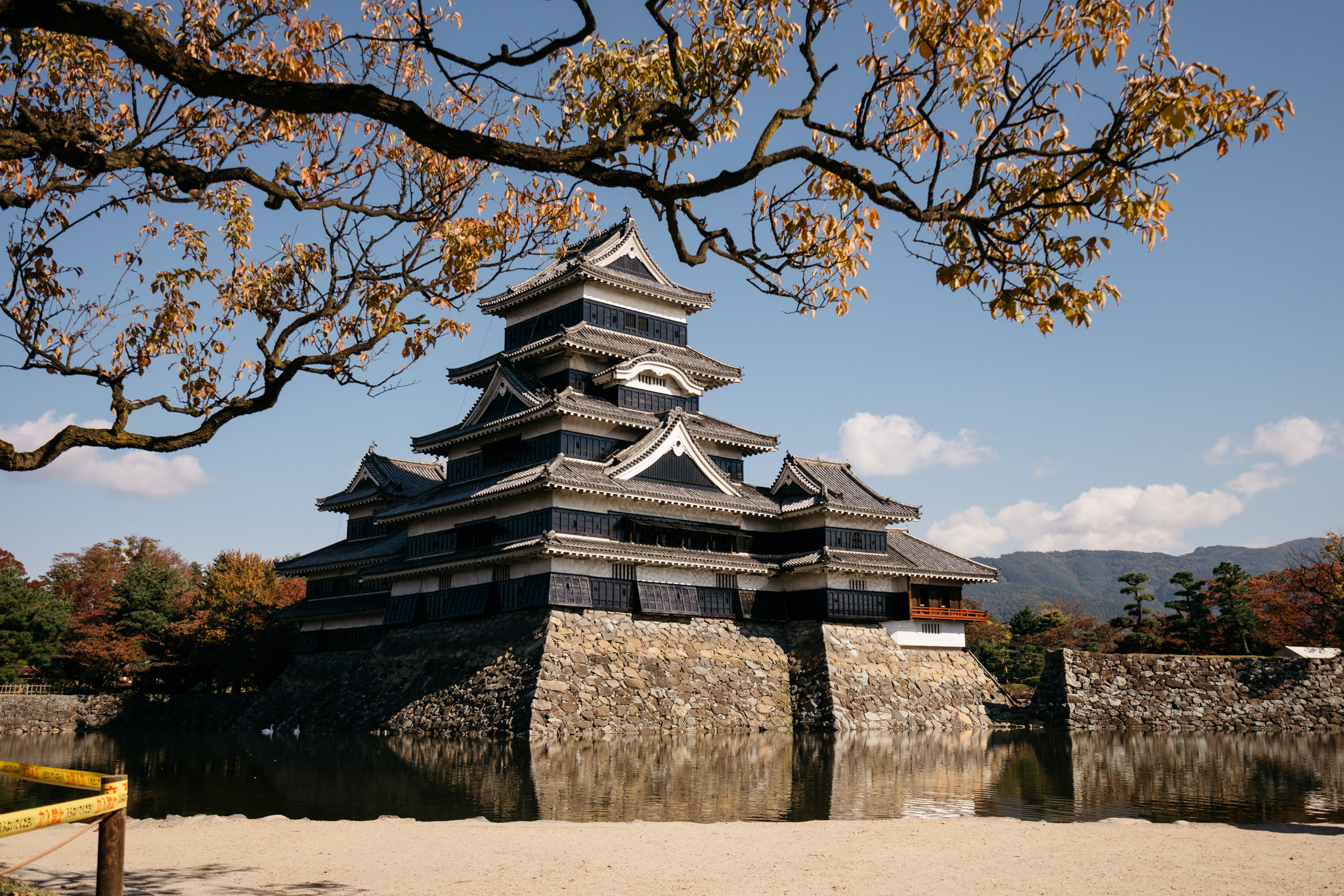 Matsumoto Castle in autumn, reflected in a moat.