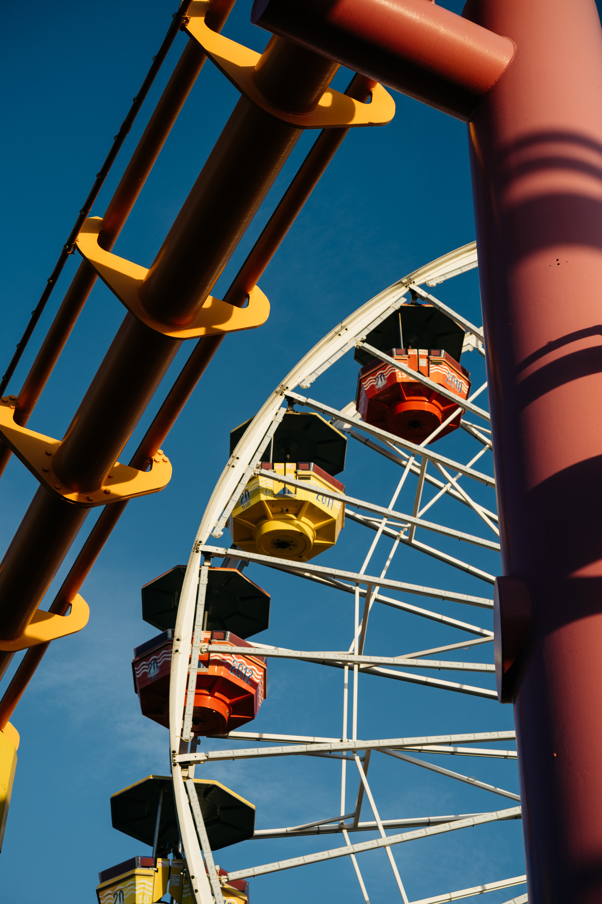 Roller coaster track and Ferris wheel gondolas against a blue sky.