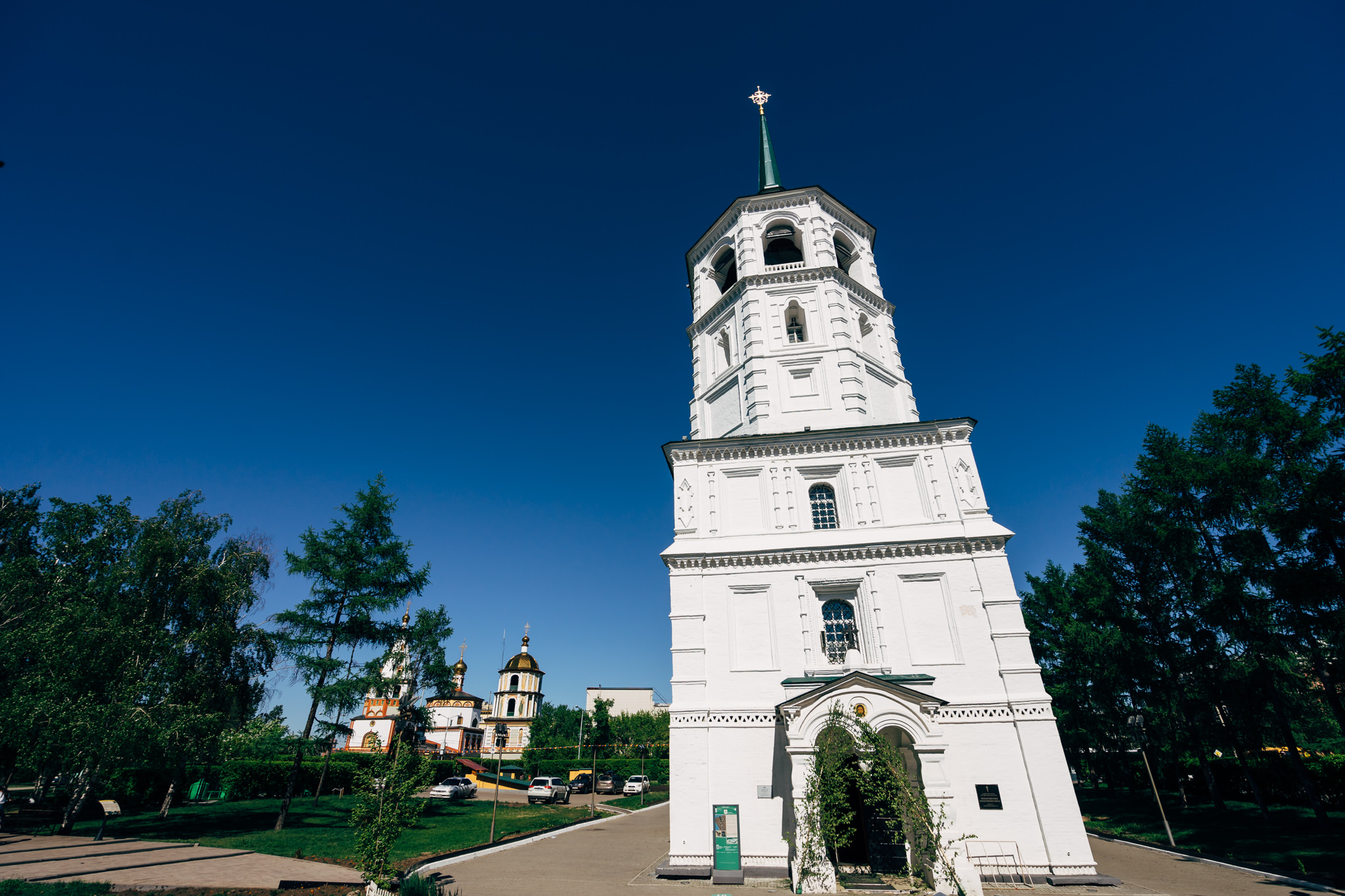 Tall white bell tower of a church in Irkutsk, Russia, with a smaller church visible in the background.