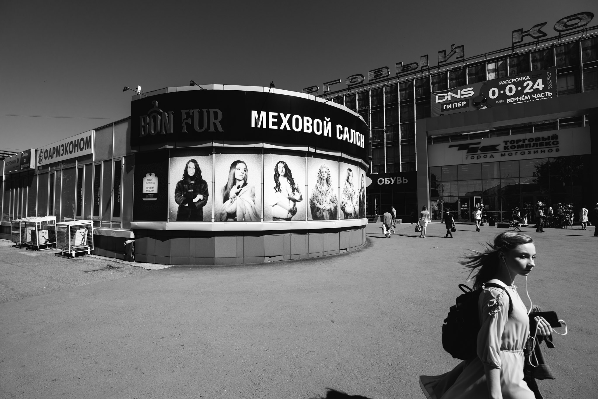 Black and white photo of a Bon Fur fur salon in Siberia, featuring a large advertisement with models in fur coats.