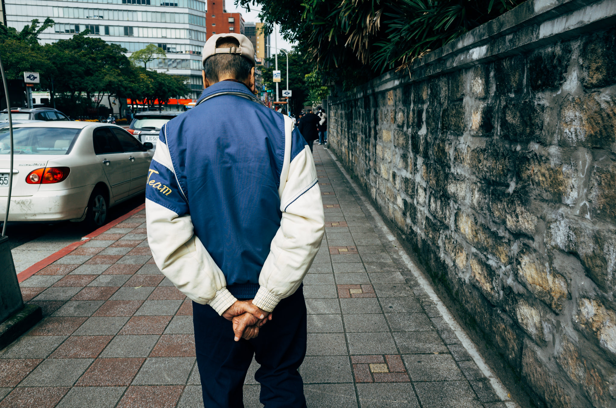 Man walking away from camera on a city sidewalk.