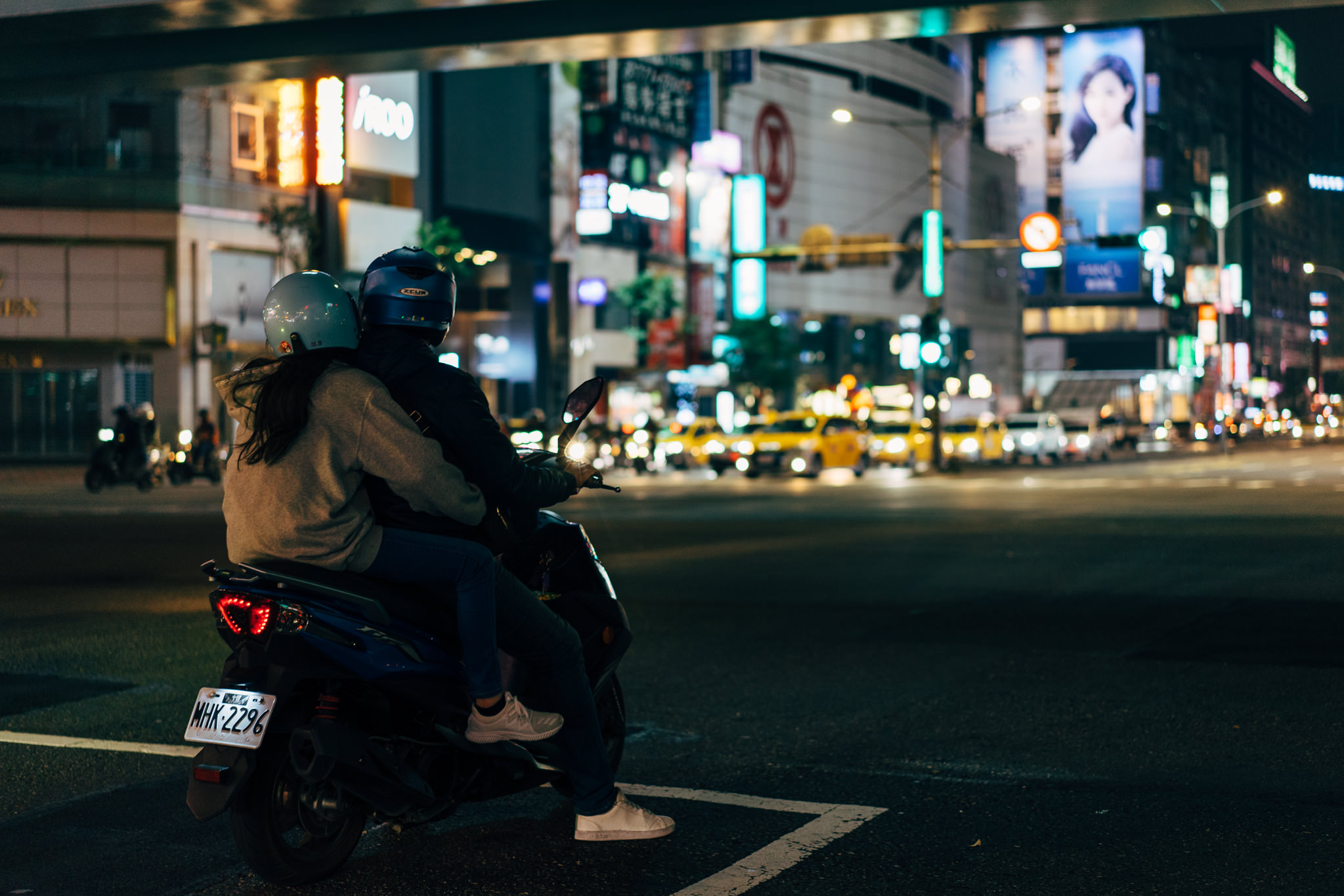Couple on scooter at night in Taipei.
