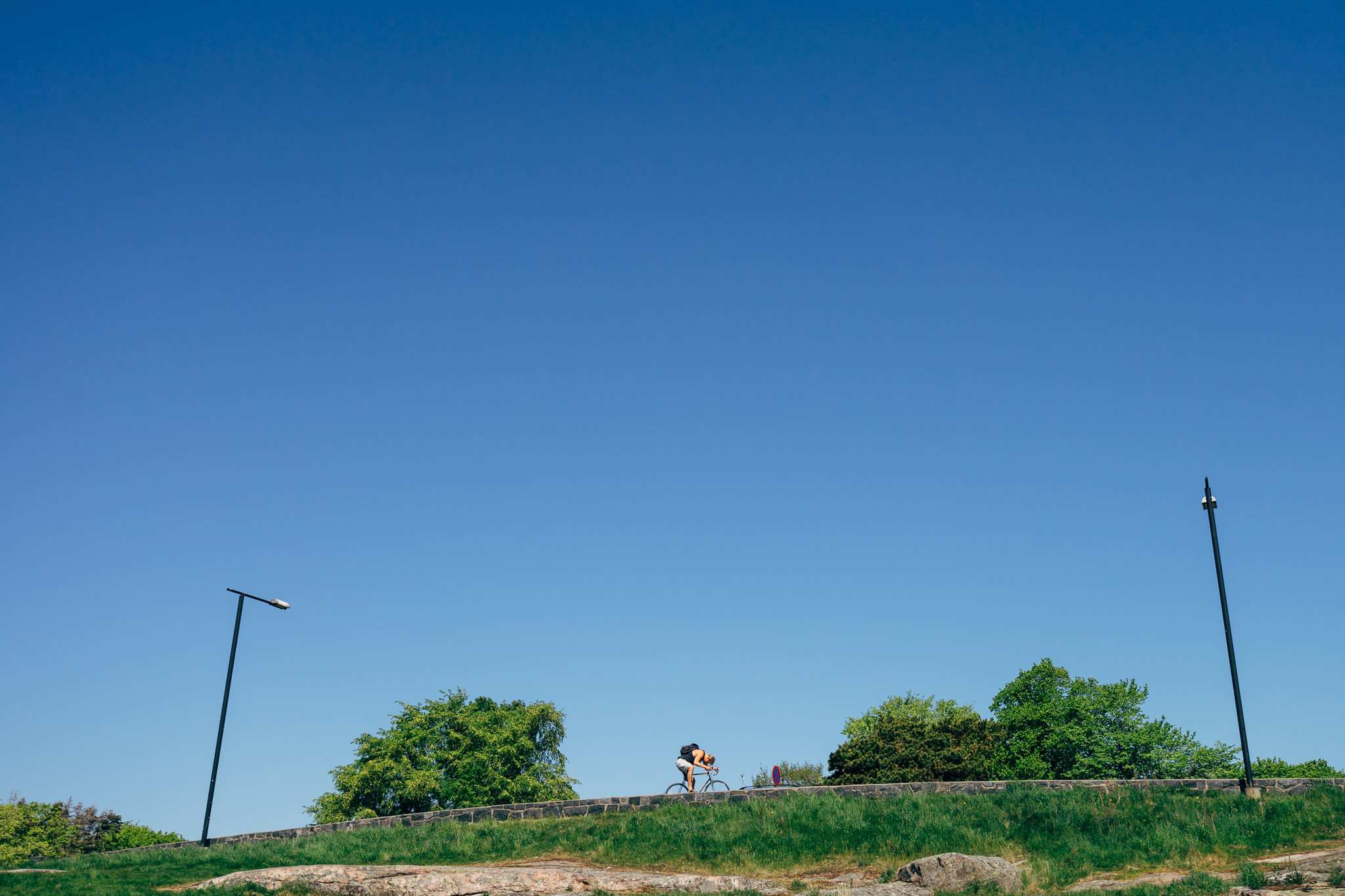 Person biking on a hill under a clear blue sky.