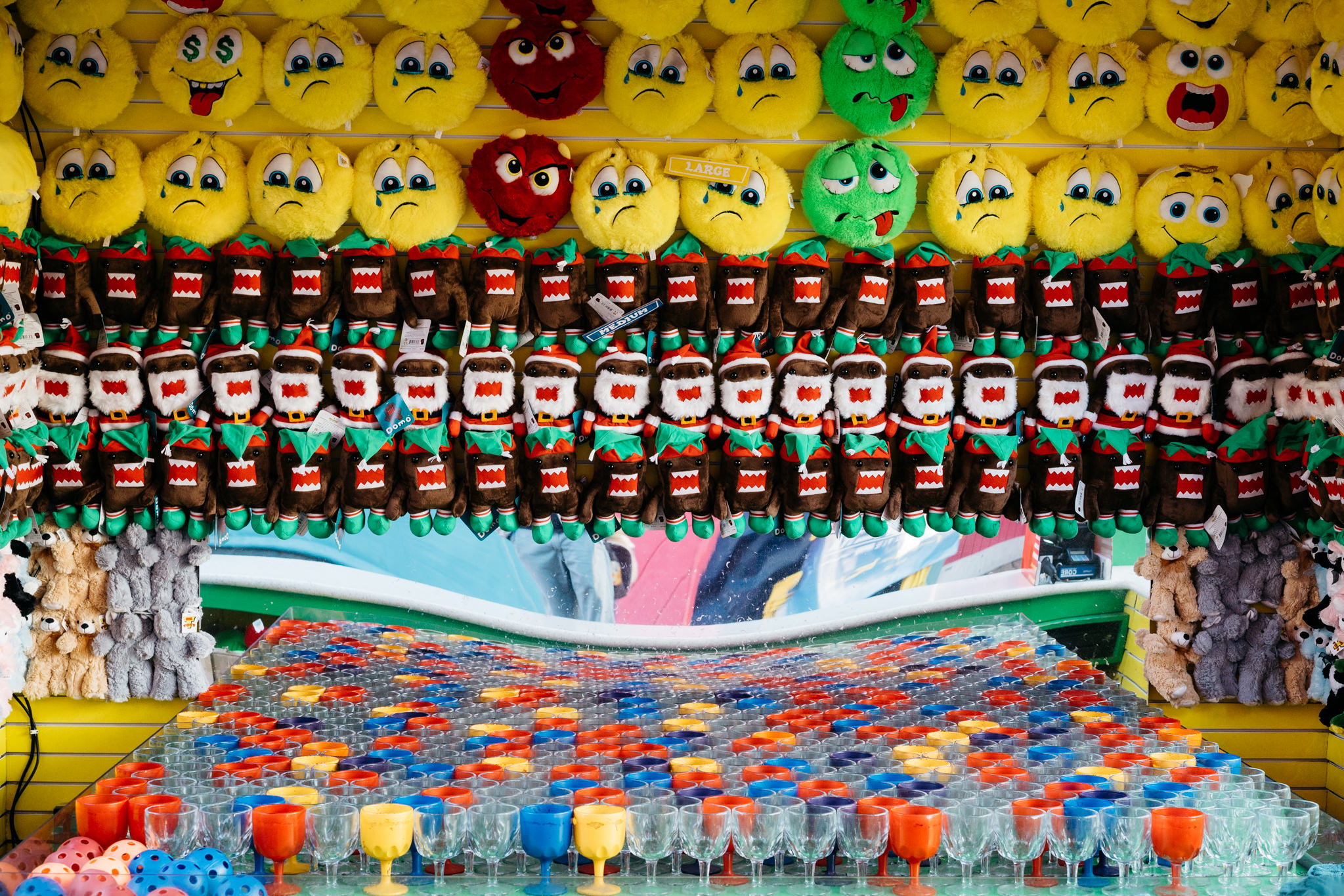 Amusement game with rows of colorful glasses and plush toys above.