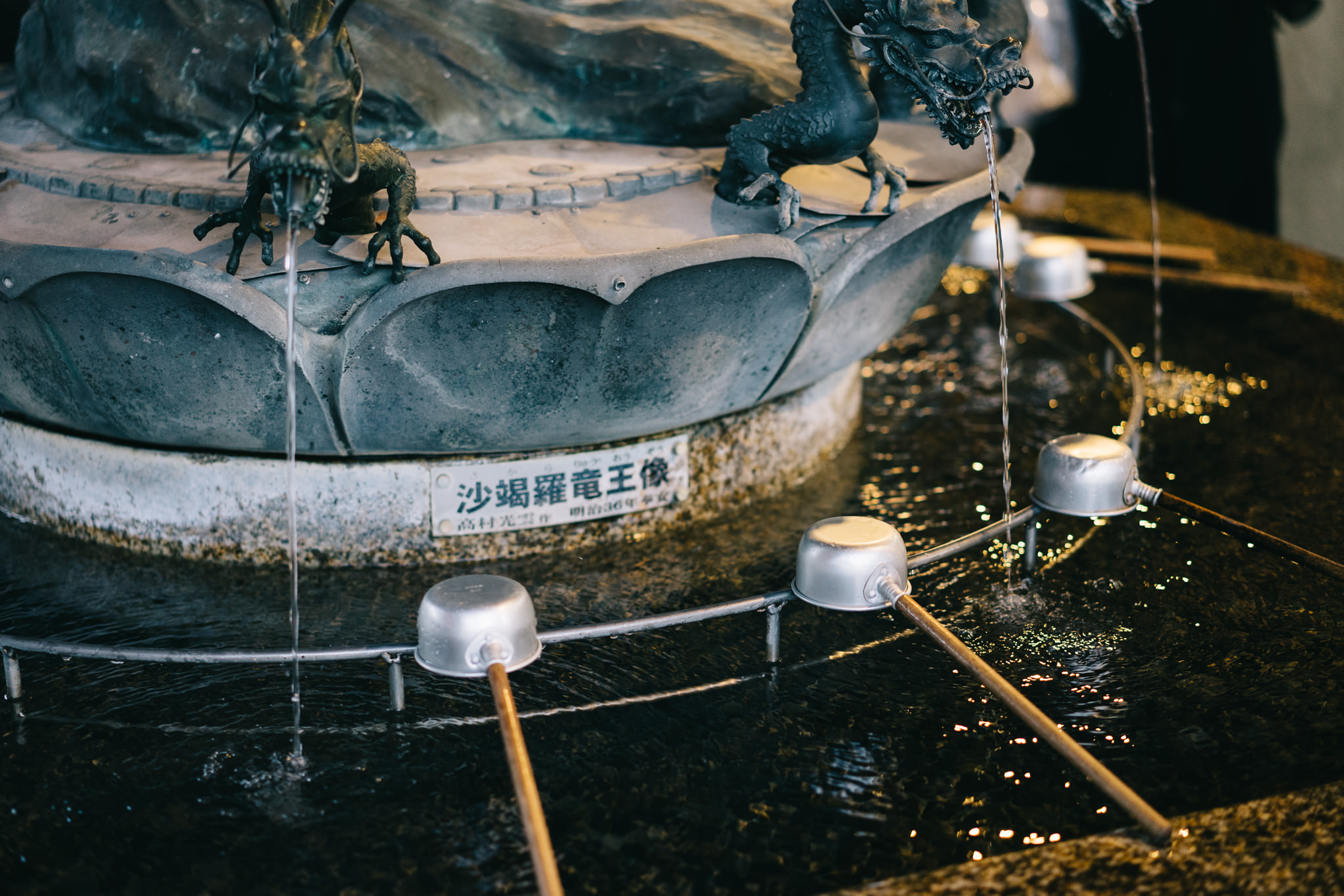 Water fountain at Sensoji Temple in Asakusa with dragon statues pouring water into a basin with ladles.