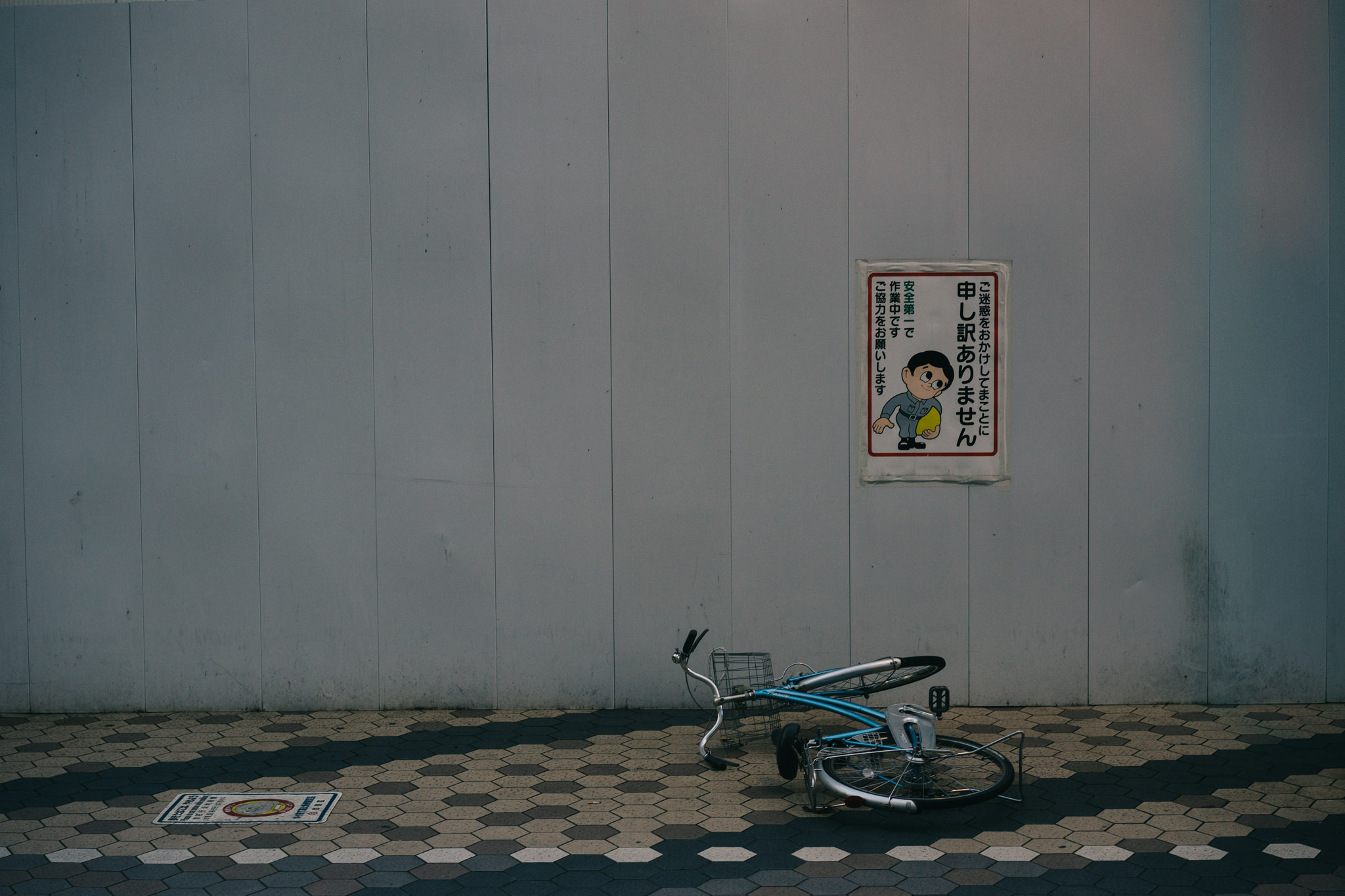 Fallen bicycle next to a sign in Japanese.