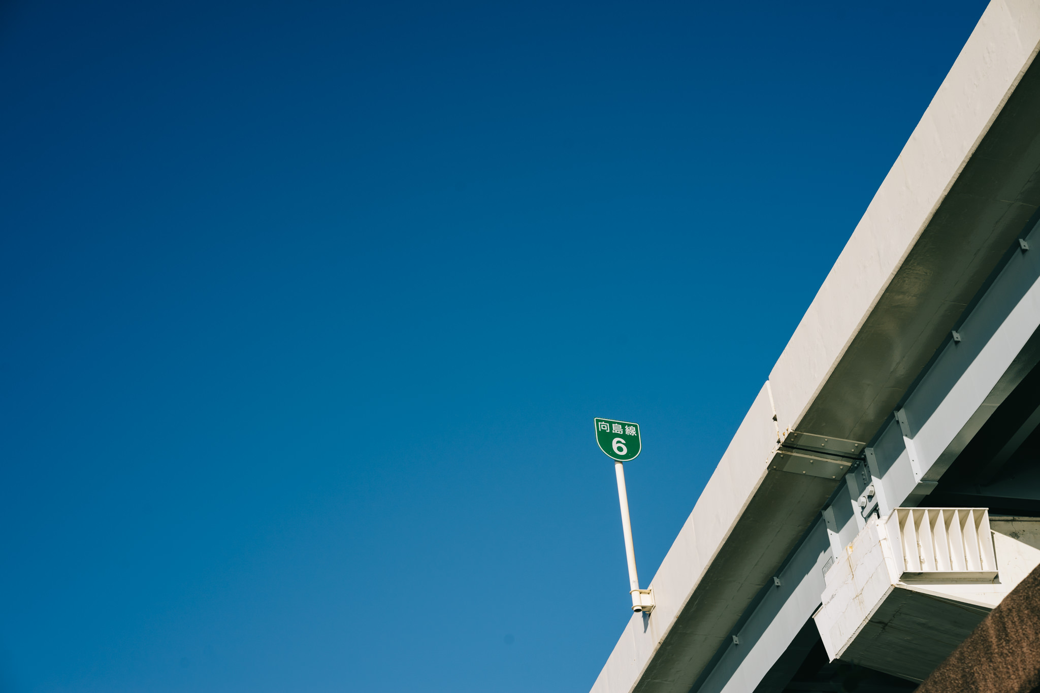 Tokyo highway bridge with route 6 sign against a blue sky.