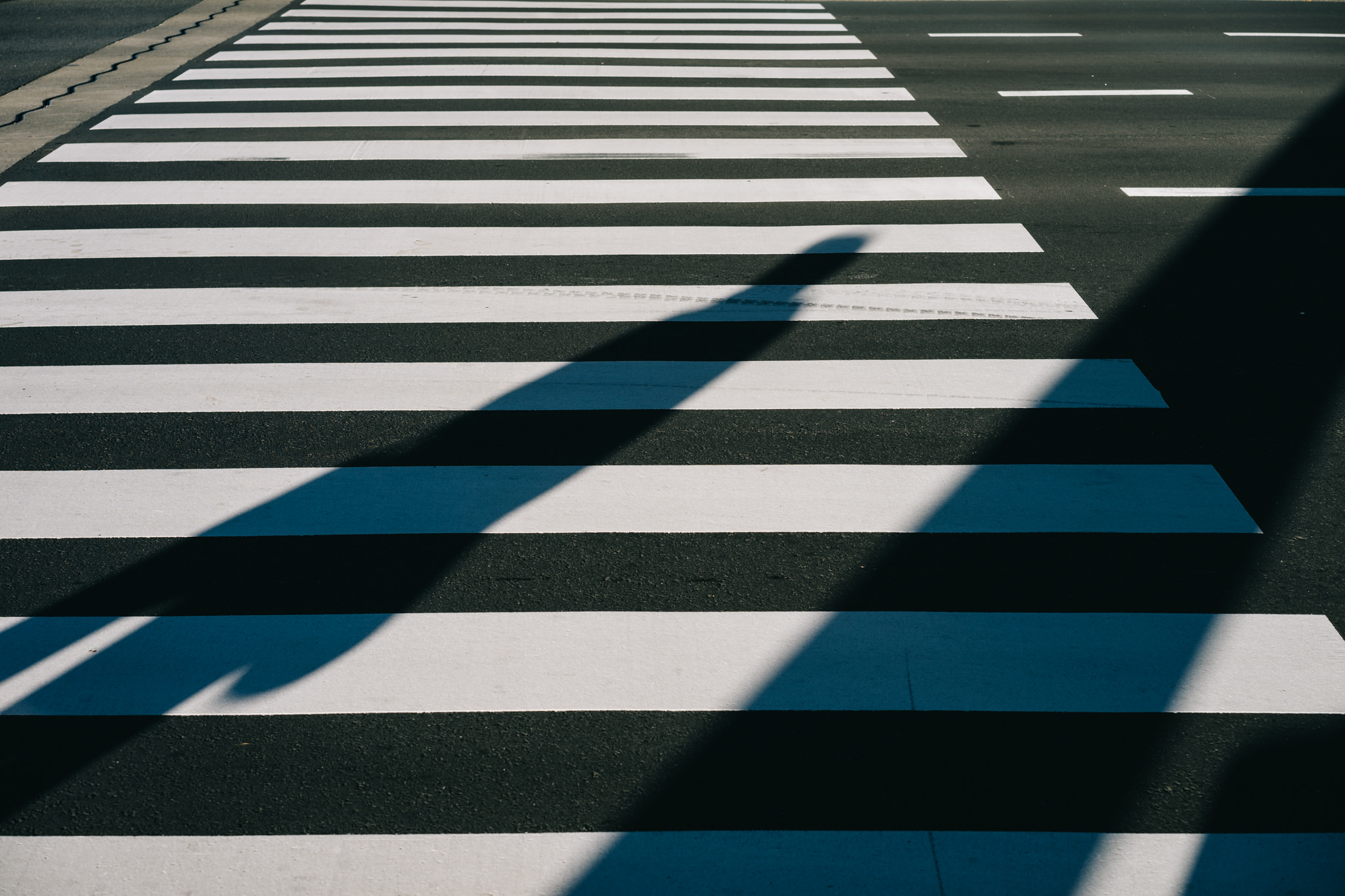 Shadow of a person crossing a pedestrian crosswalk.