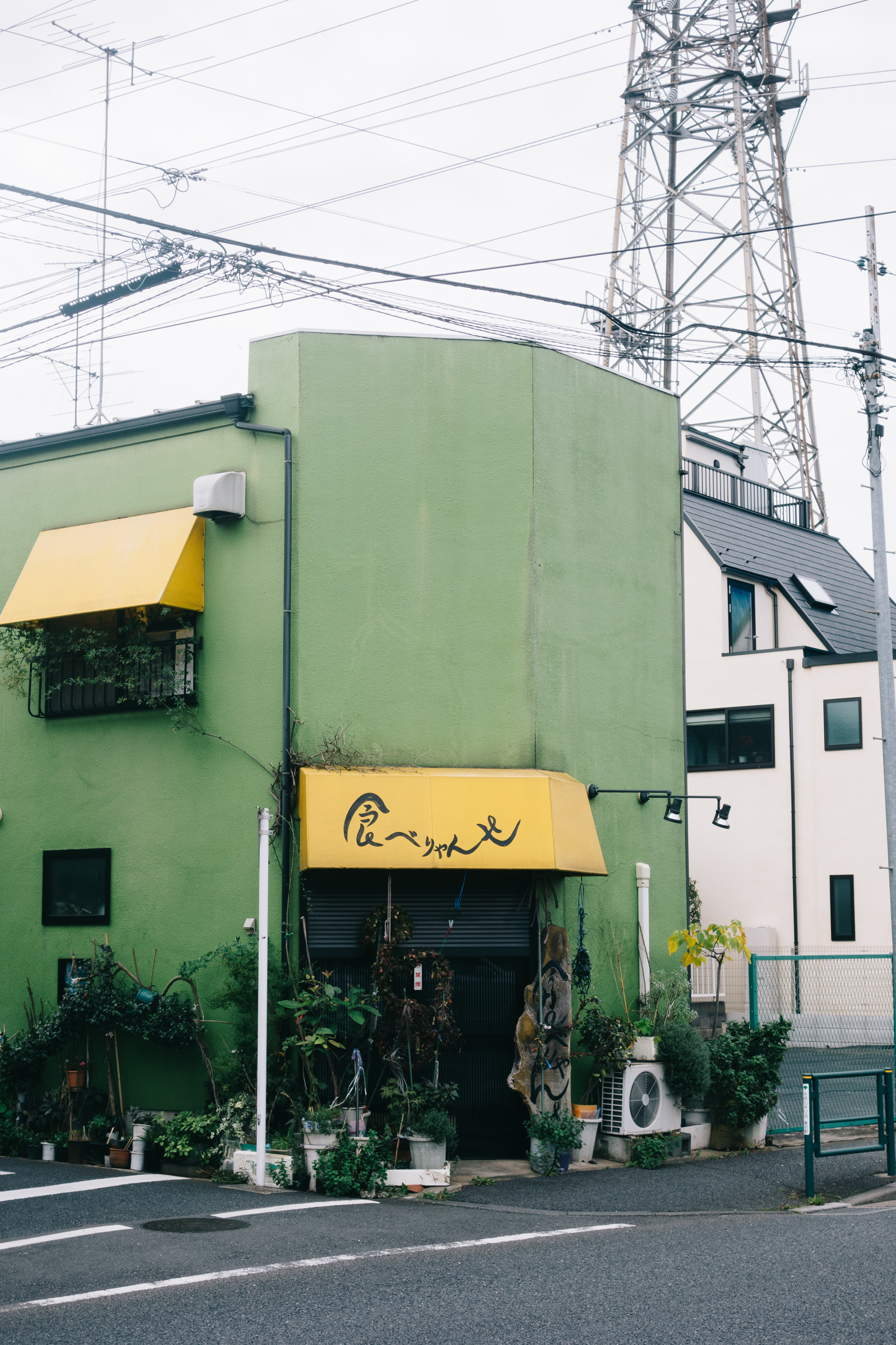 Green building with yellow awning and Japanese text in Tokyo.