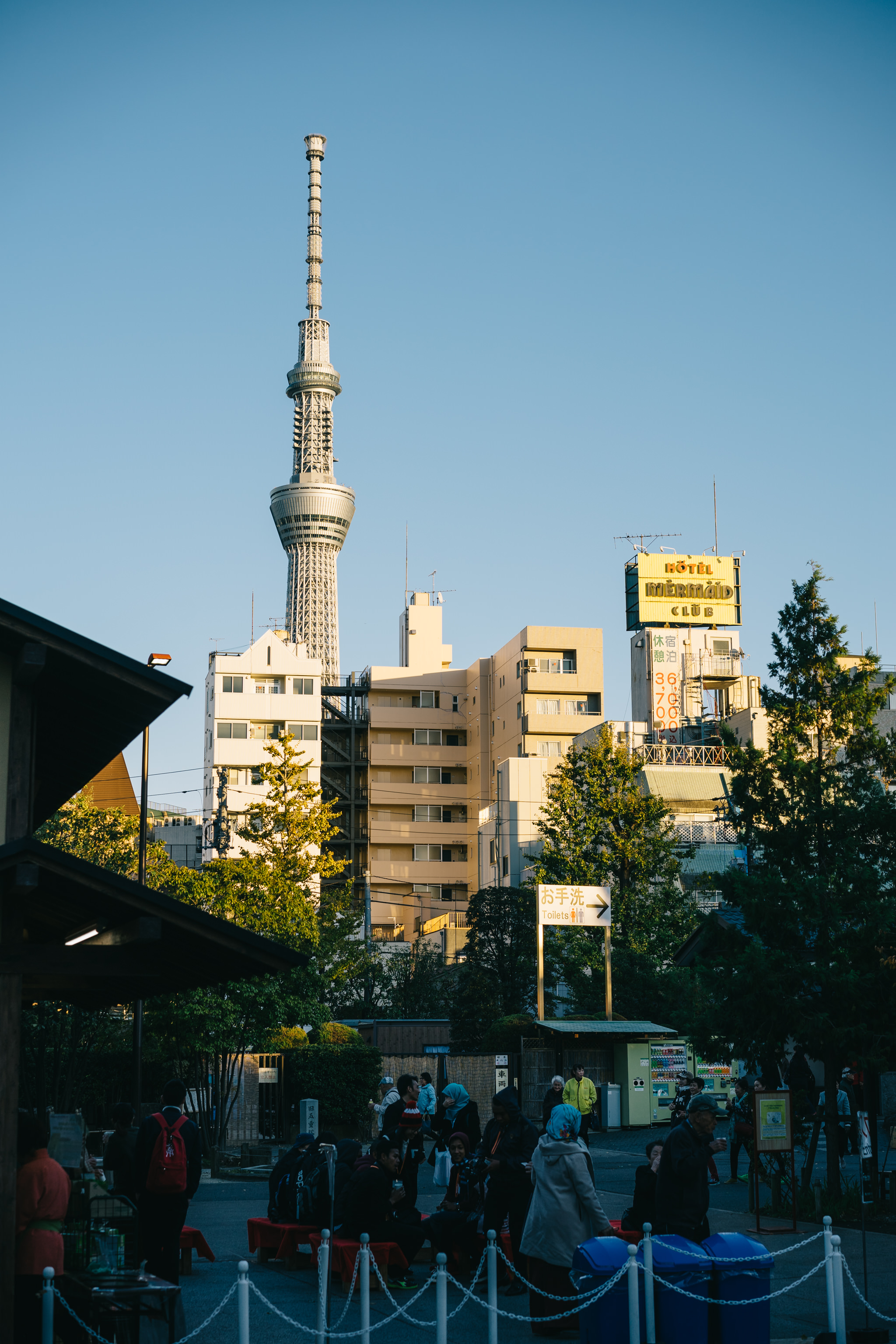 Tokyo Skytree viewed from street level, with buildings and people in the foreground.