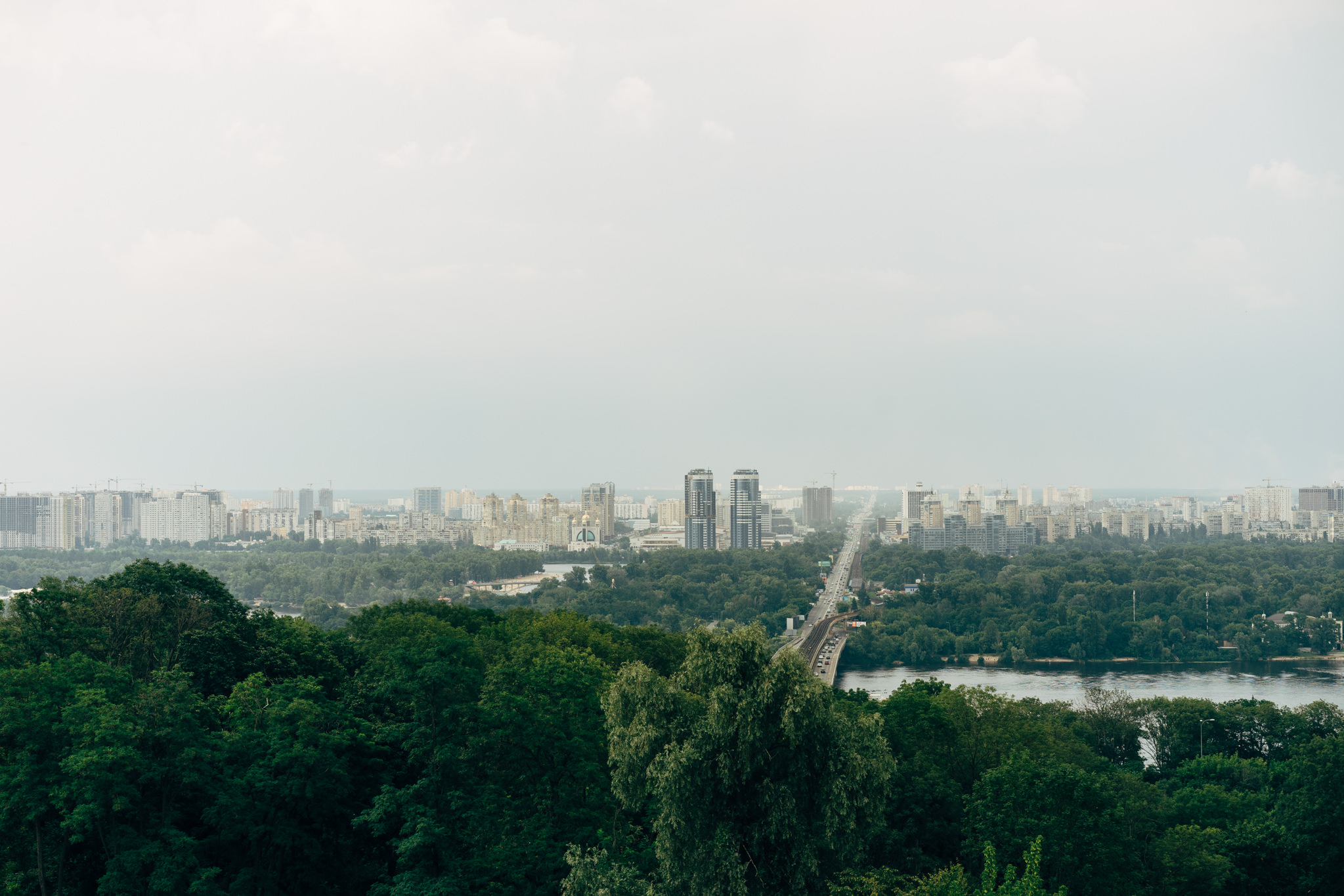 Aerial view of Kyiv, Ukraine: city skyline, river, and lush green landscape.