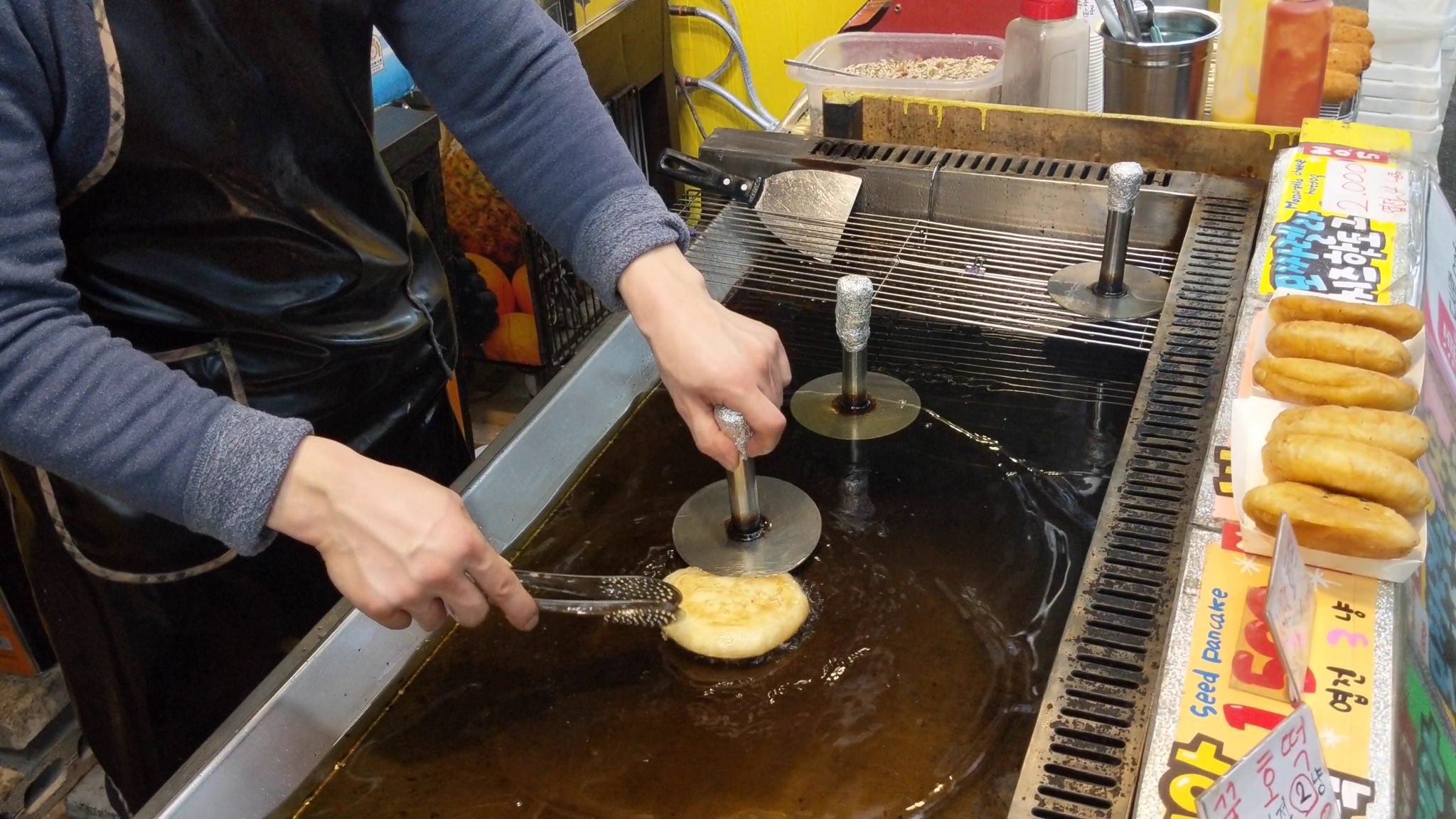 Person frying hotteok, a Korean street food.