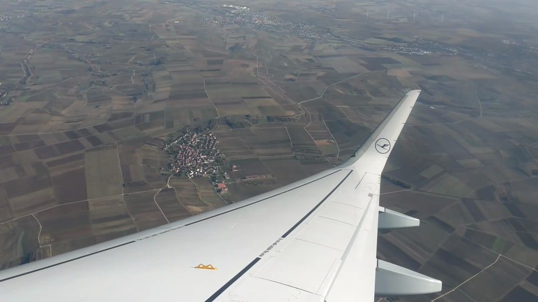 Airplane wing over rural landscape.