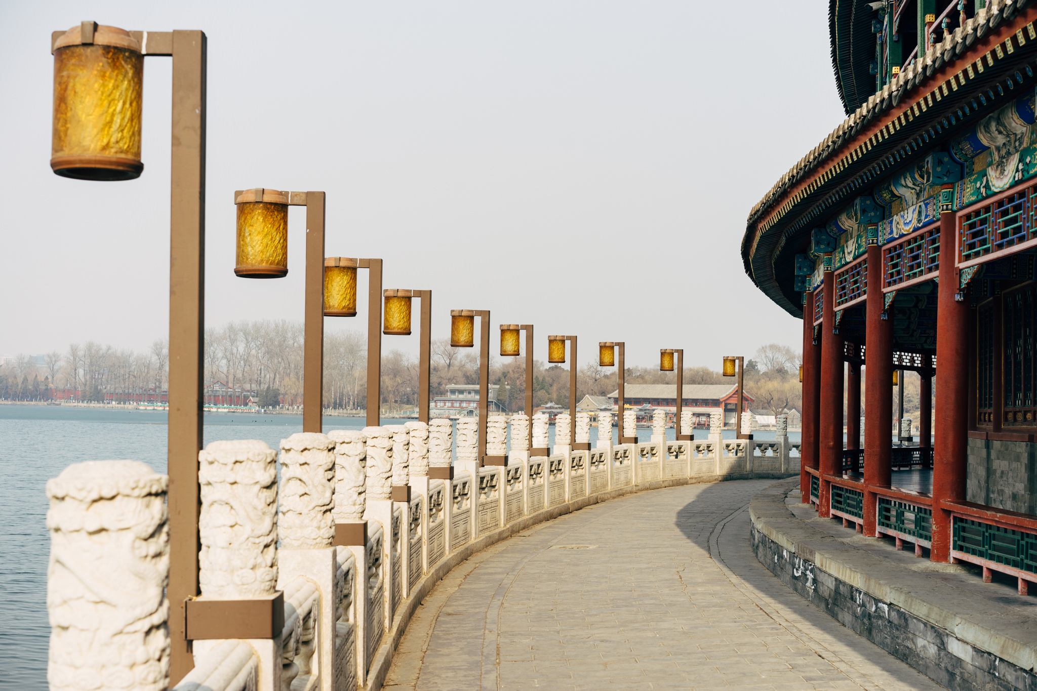 Curved walkway with ornate stone railing and lanterns in Beihai Park, Beijing.