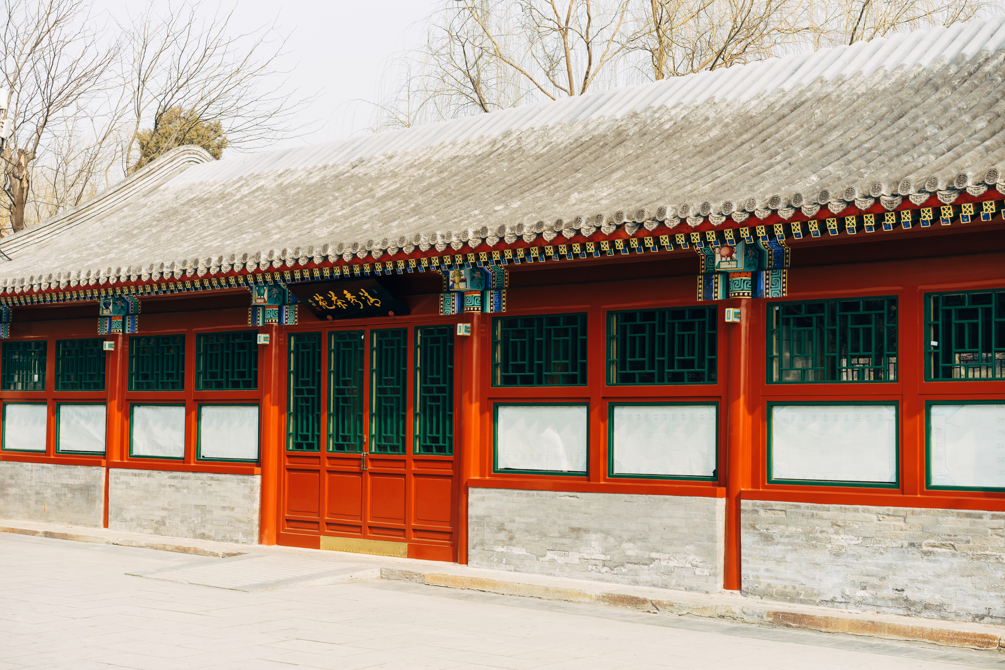Red building with green windows and grey roof in Beihai Park, Beijing.