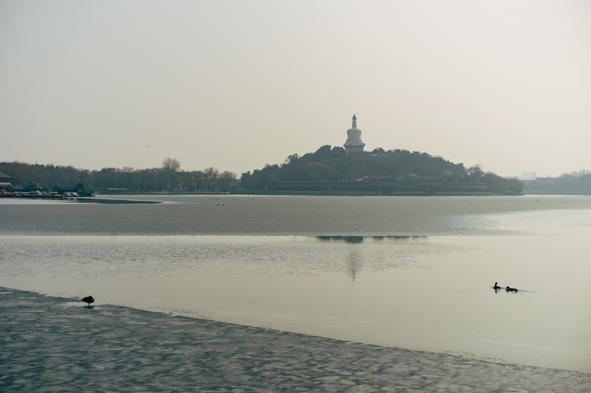 Beijing's Beihai Park: White pagoda on island in partially frozen lake.