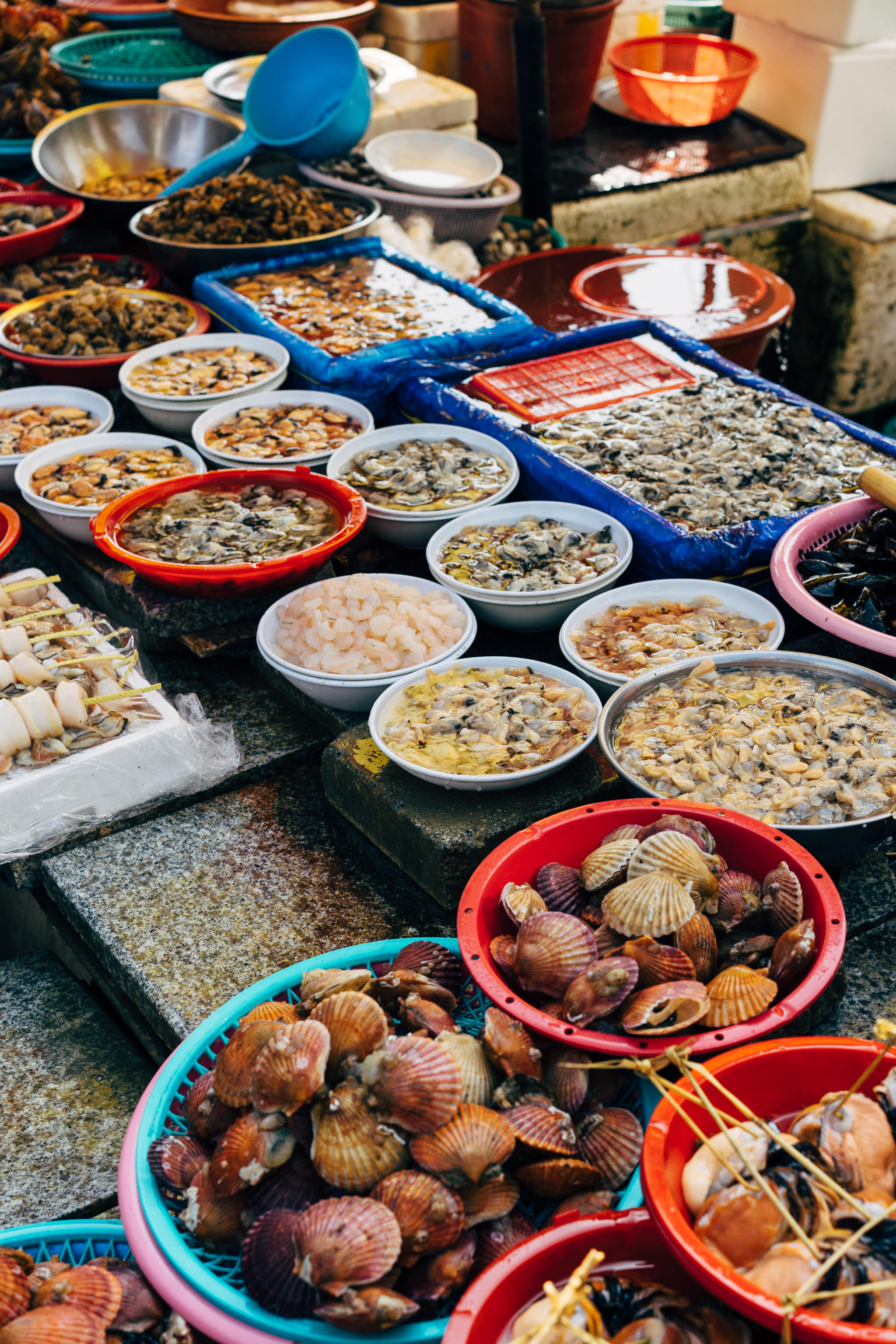 Busan fish market with various seafood in bowls and baskets.