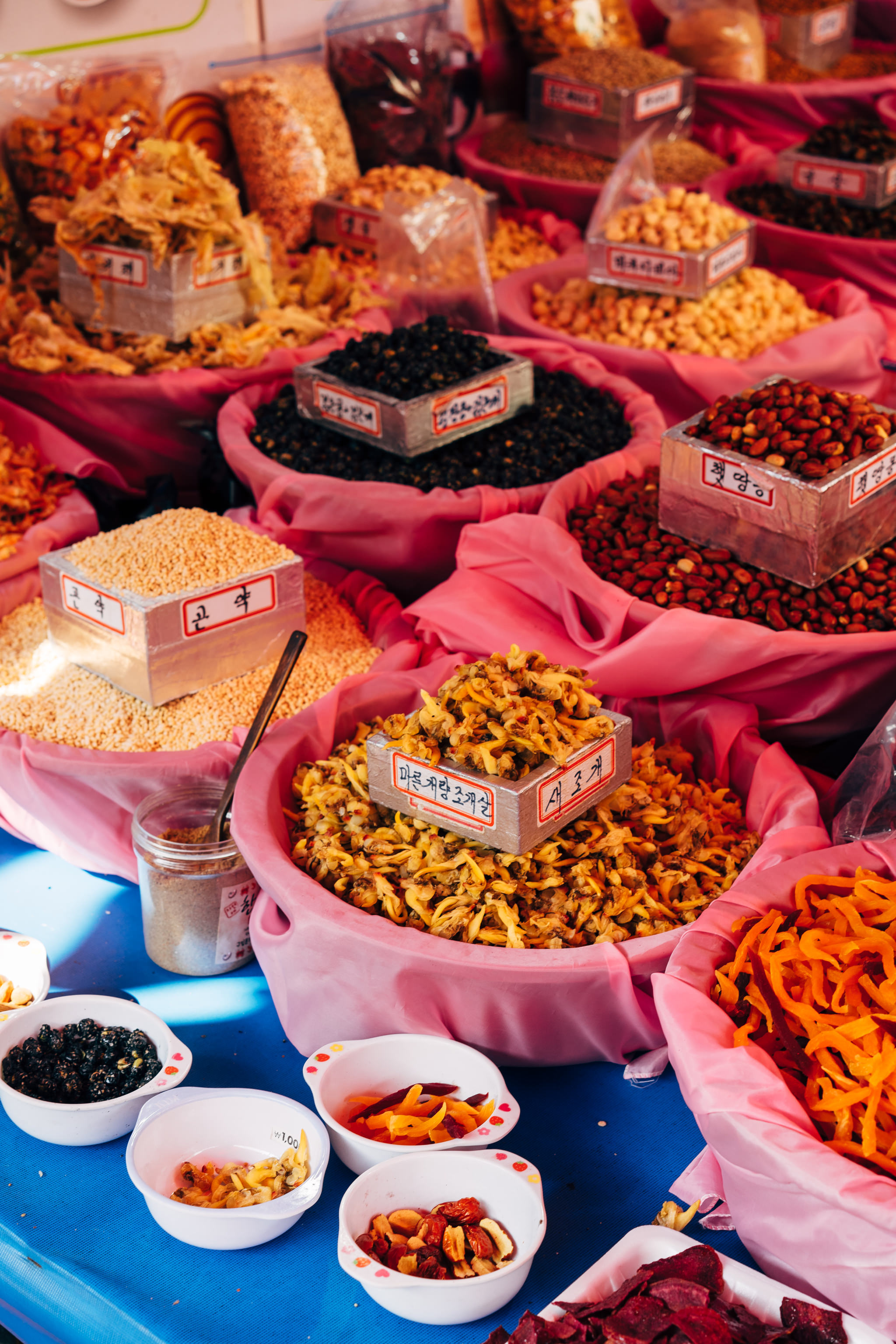 Busan fish market: various dried seafood and nuts in pink bowls.