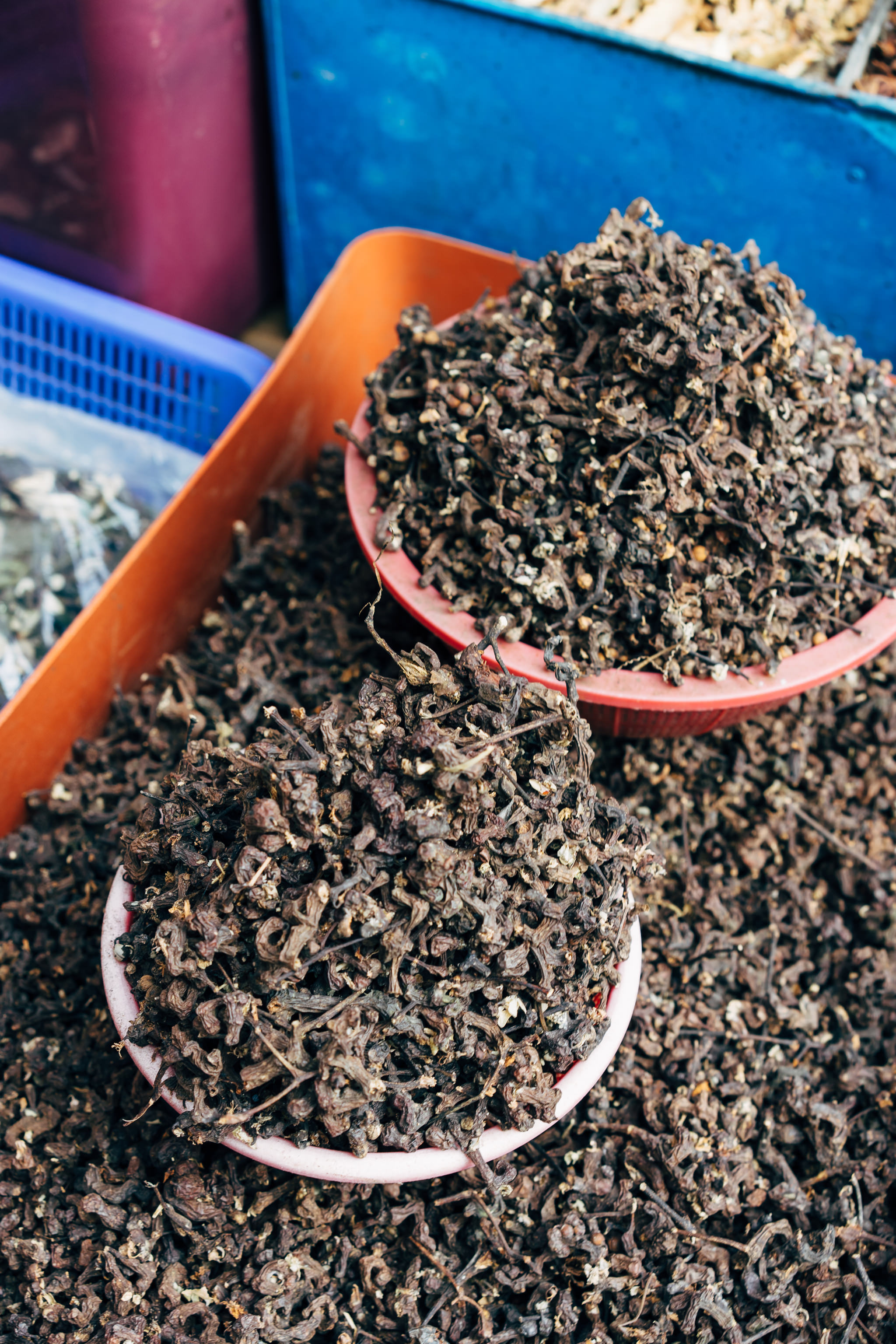 Dried herbs in pink and red bowls at Busan fish market.