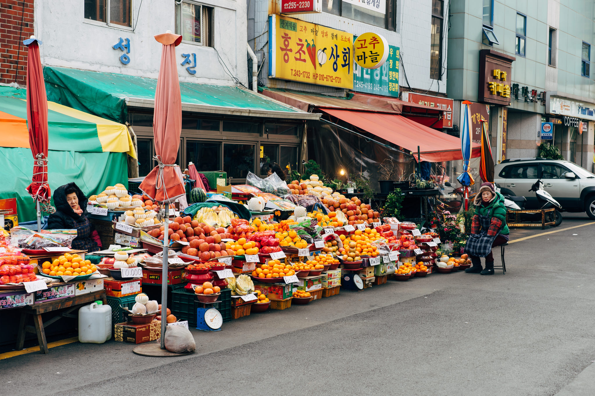 Busan market fruit stand with vendors and various fruits for sale.