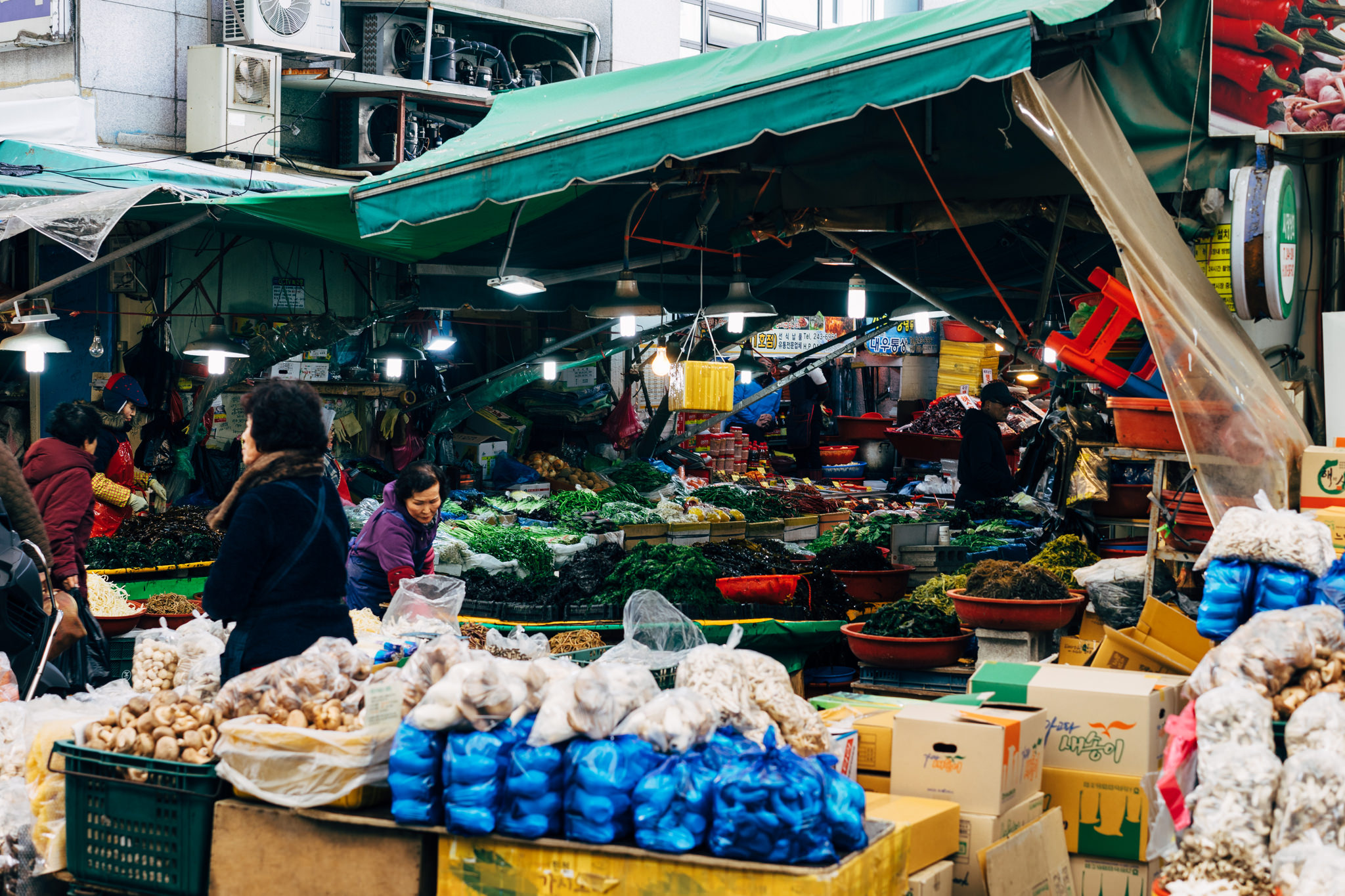 Busy Busan market stall overflowing with fresh produce and dried goods.