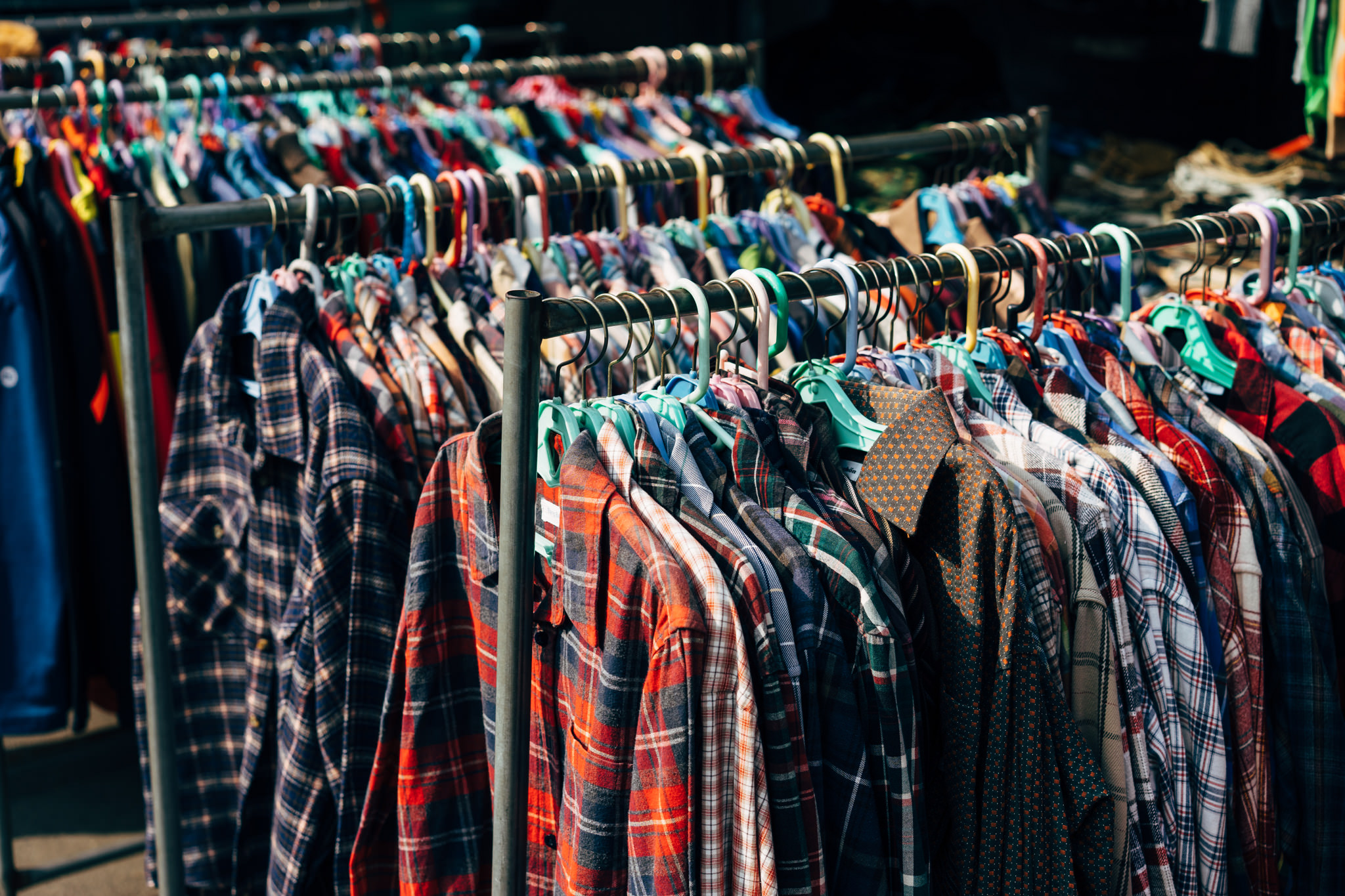 Men's plaid shirts hanging on racks at a market.