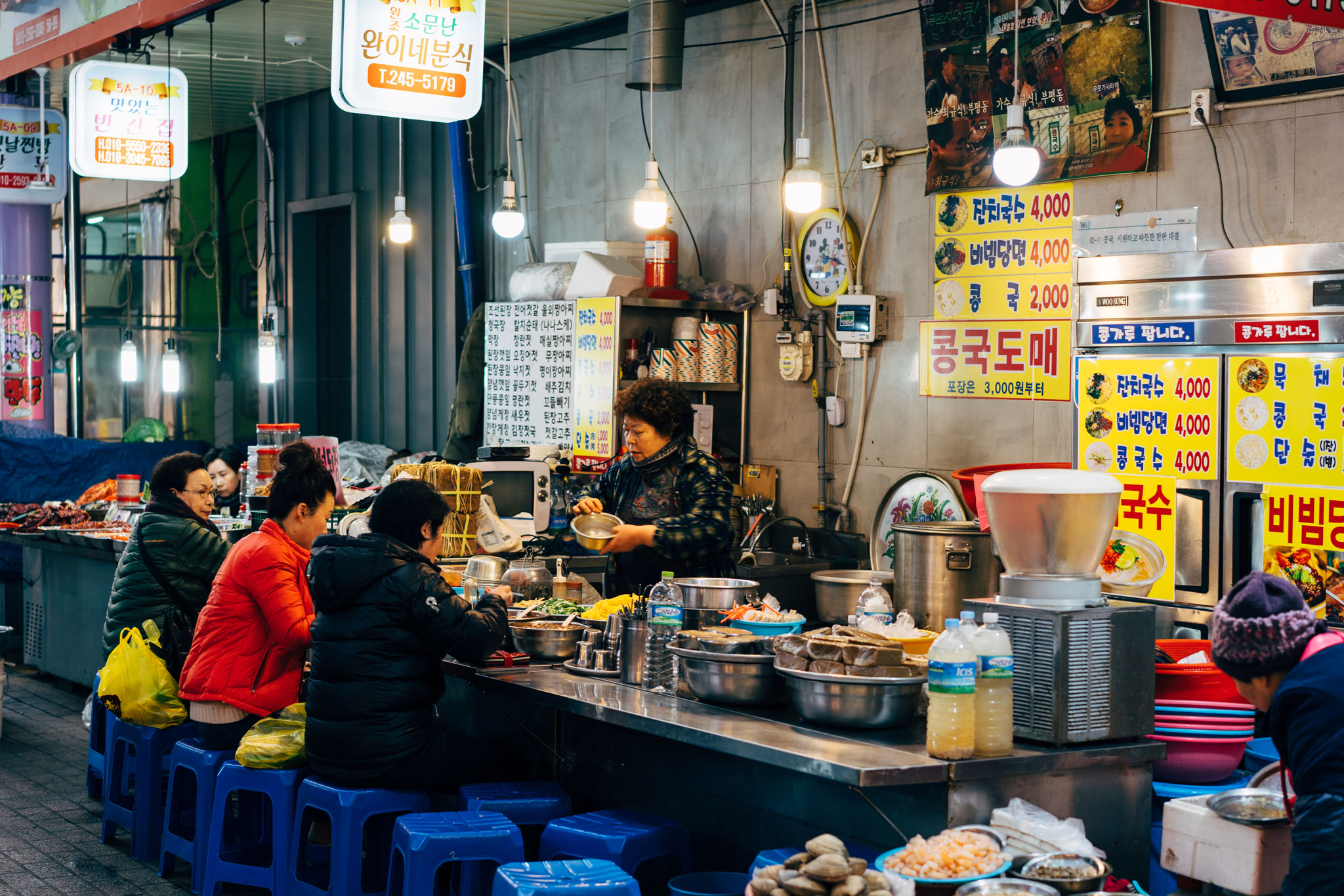 Busy Busan market food stall with a woman serving customers.
