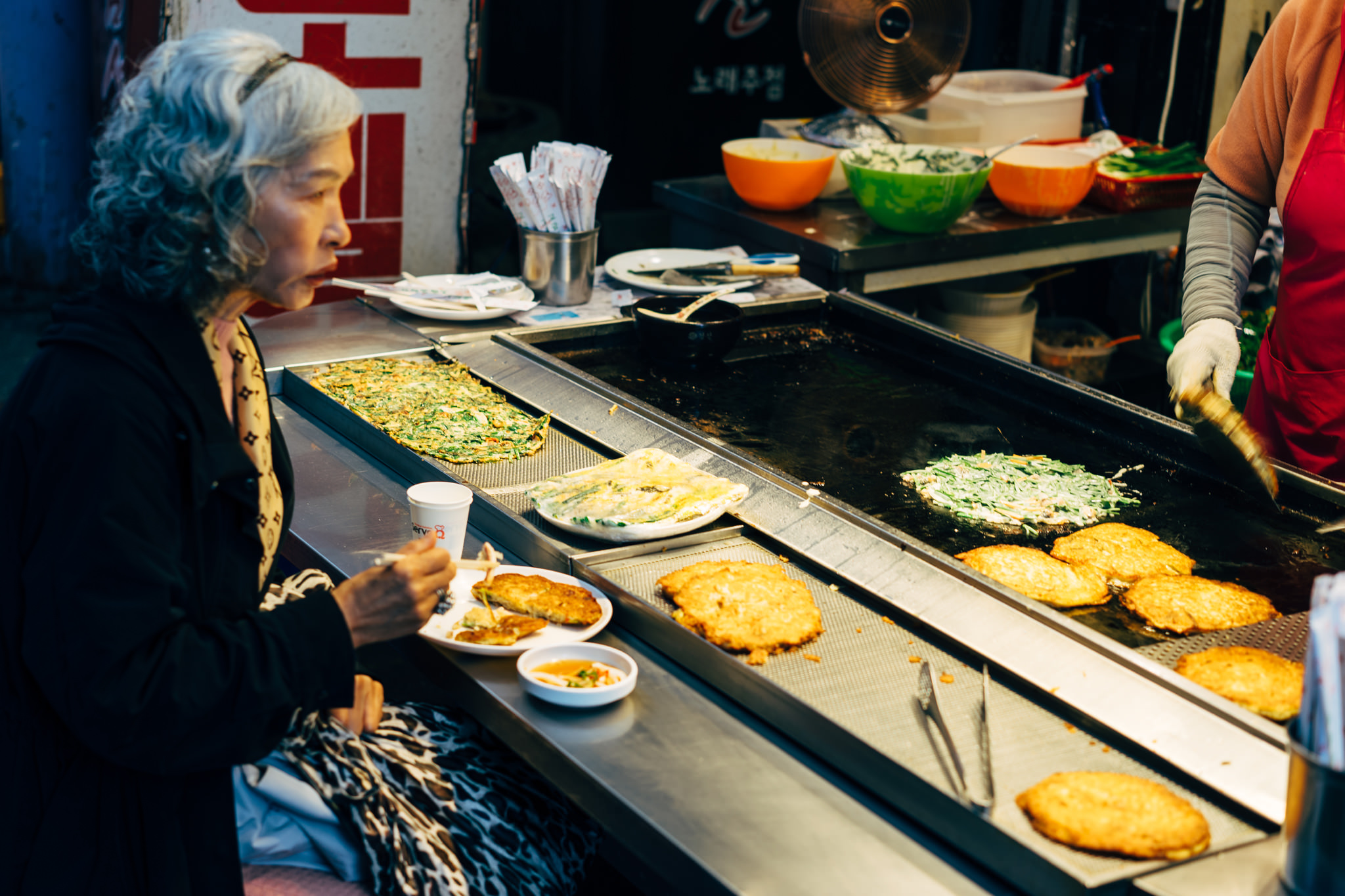 Woman eating Korean pancakes at a Busan market.