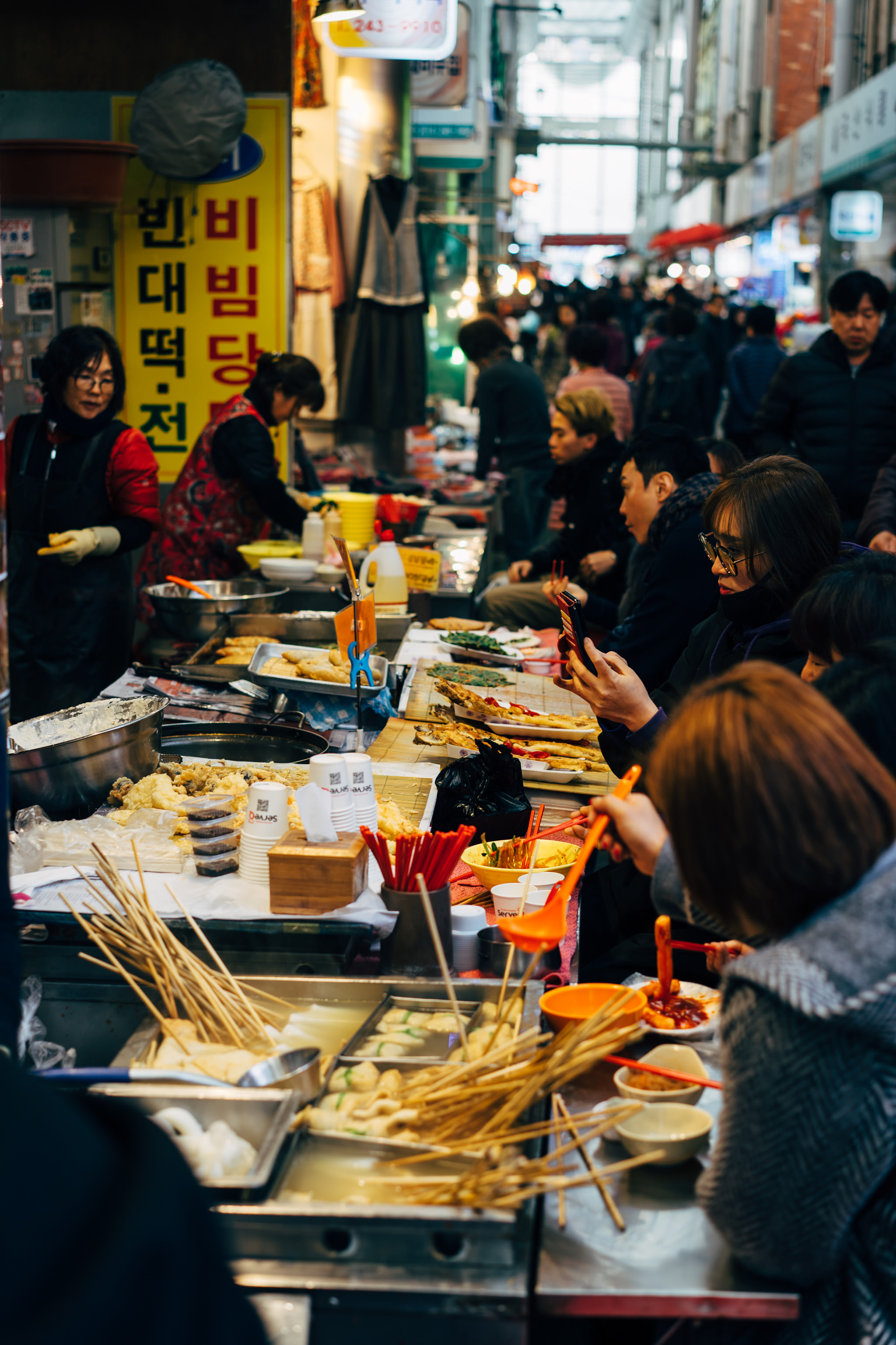 Busy Busan market food stall with various Korean street food dishes.