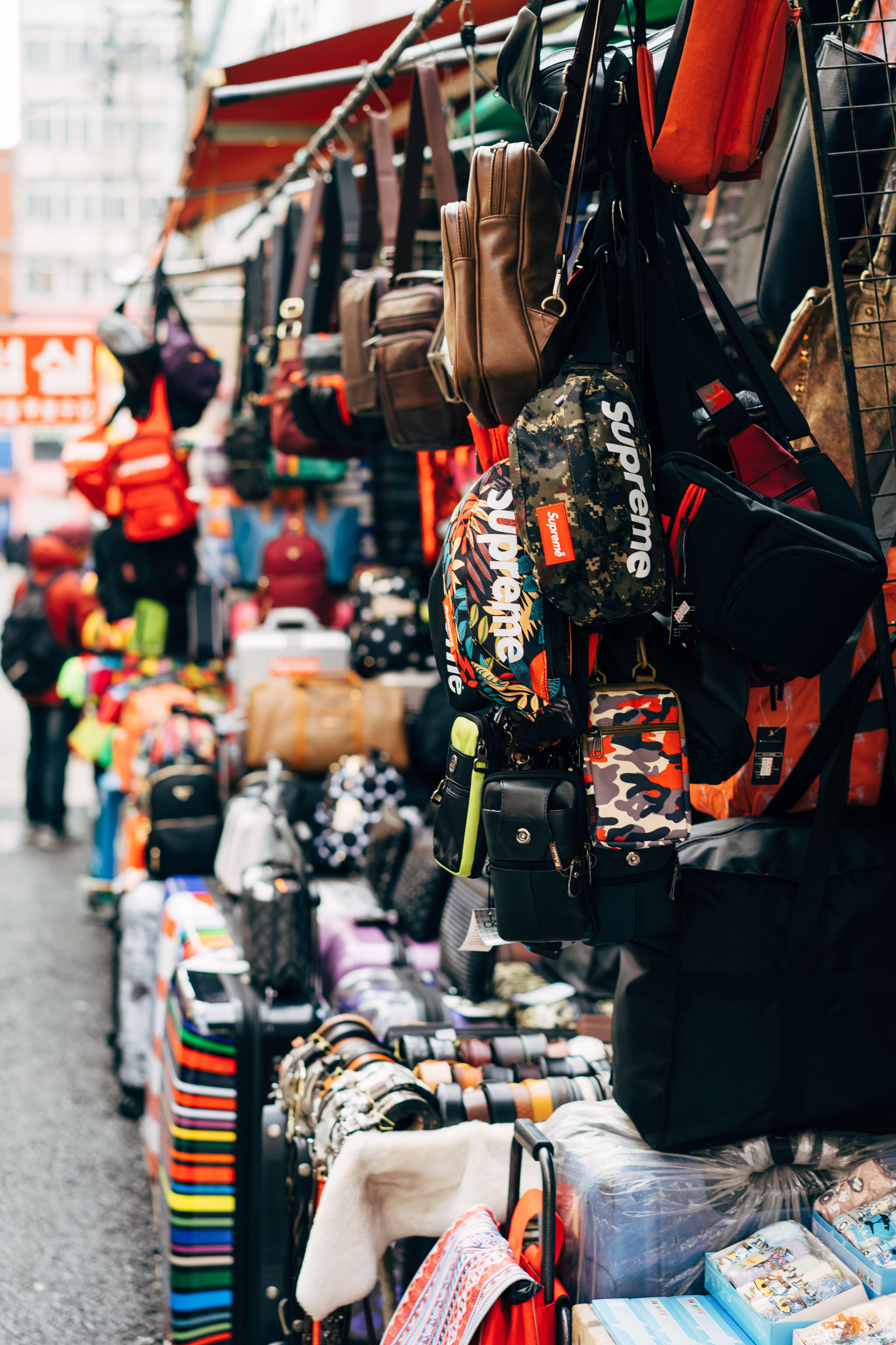 Various bags and luggage displayed at a Busan market.