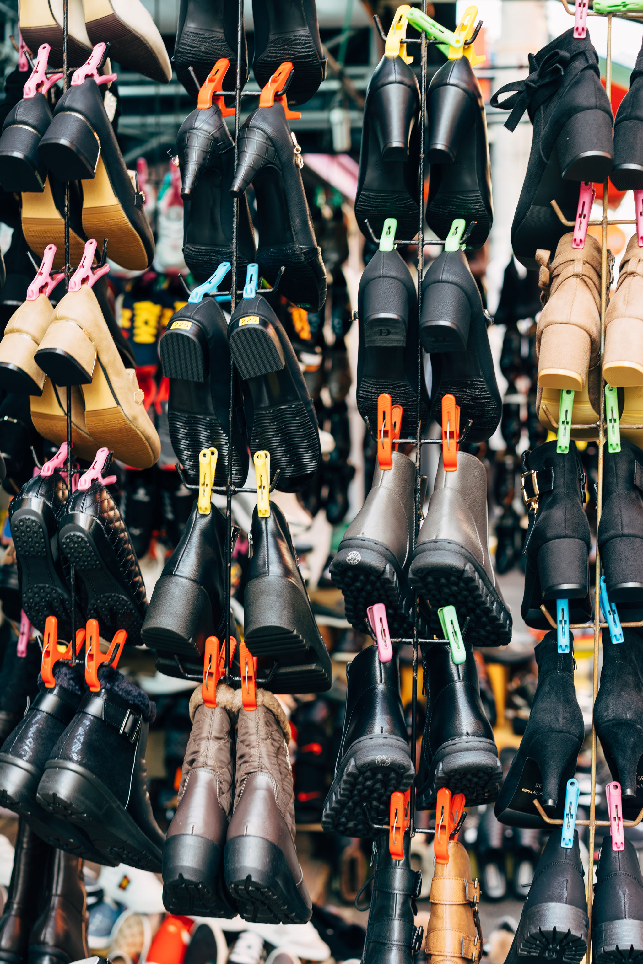 Various shoes hanging on a rack at a Busan market.