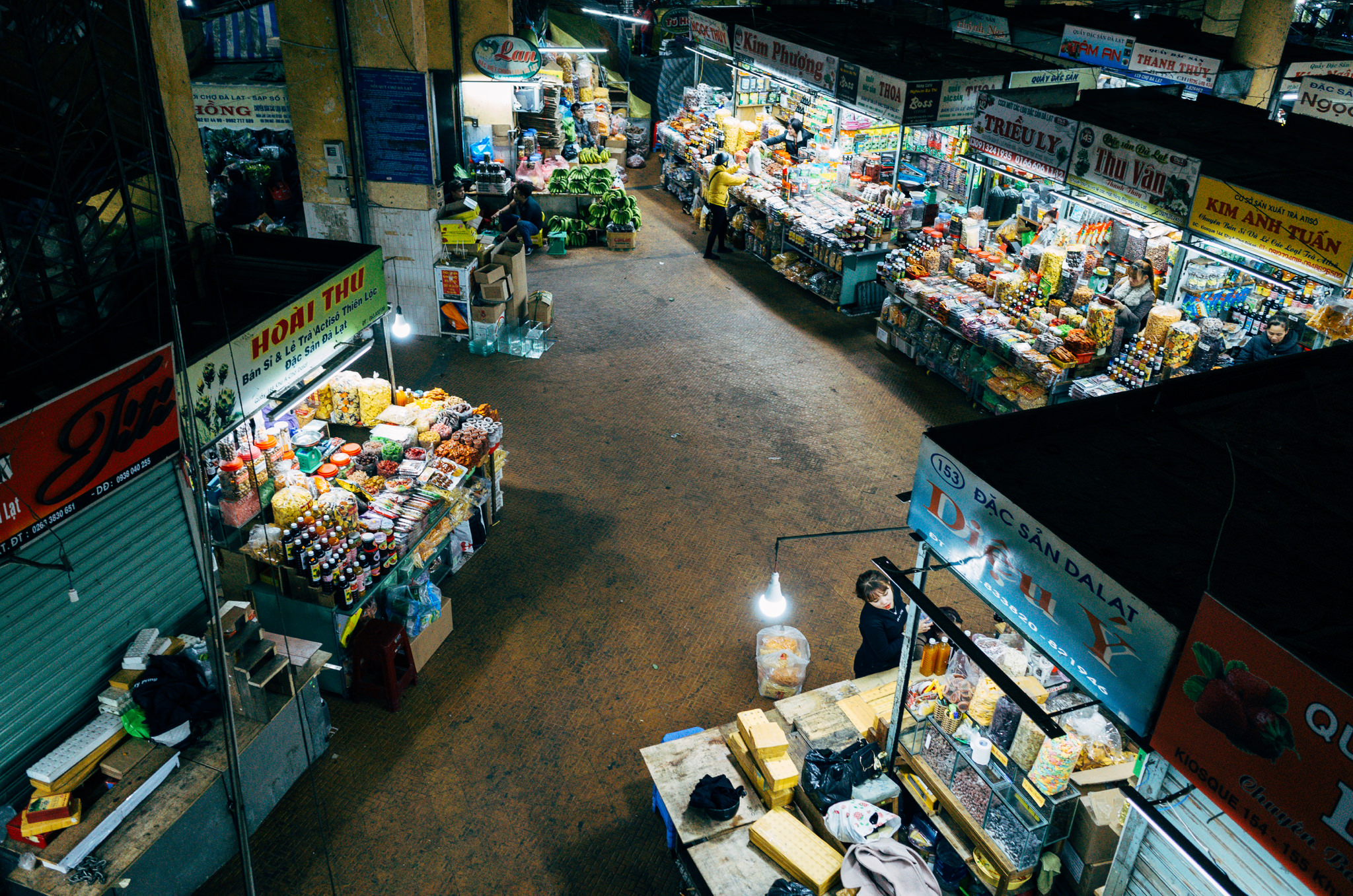 Overhead view of a bustling night market in Da Lat, Vietnam, with numerous food stalls selling snacks and drinks.