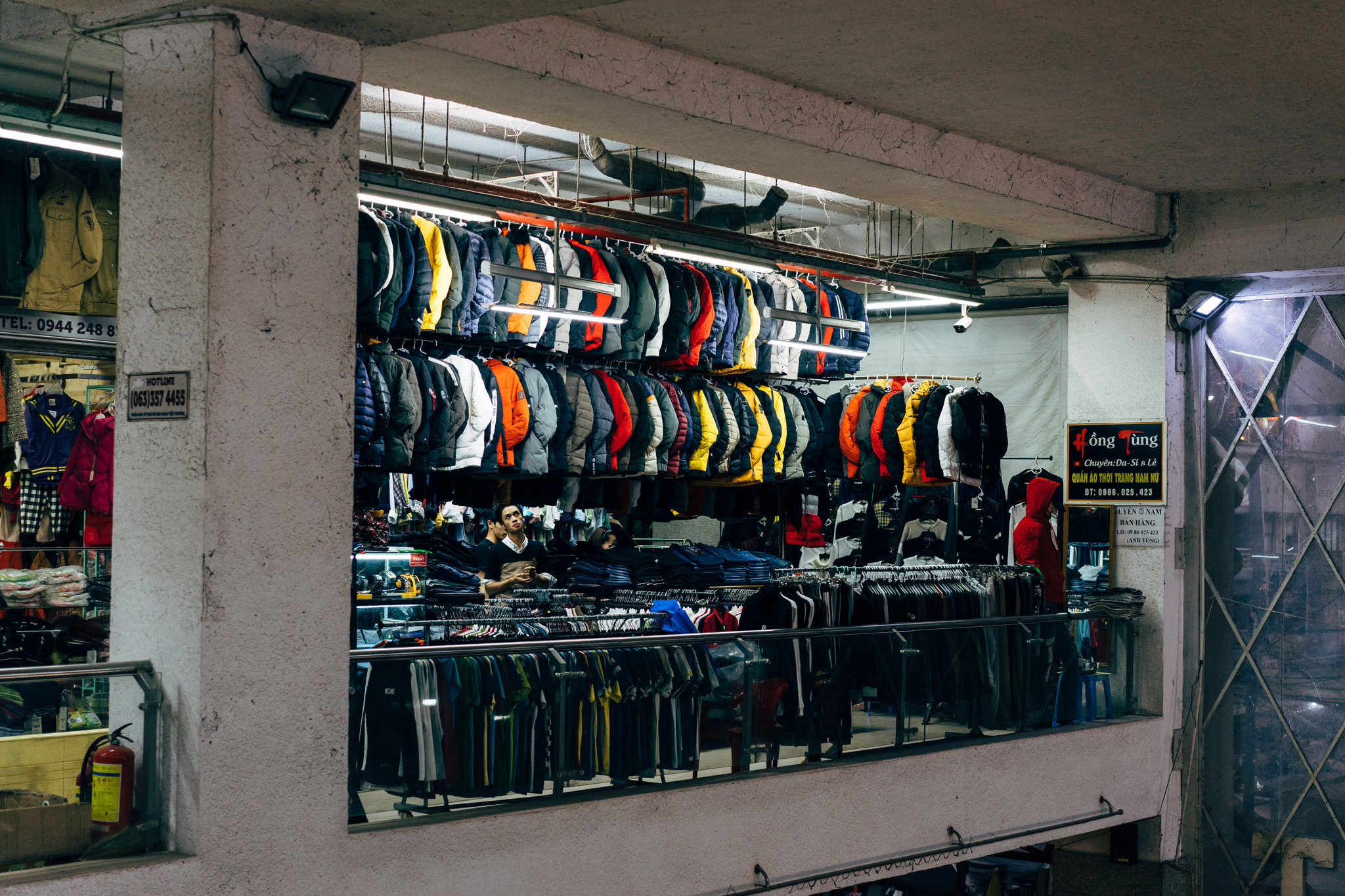 Da Lat market clothing stall with jackets and shirts on display.
