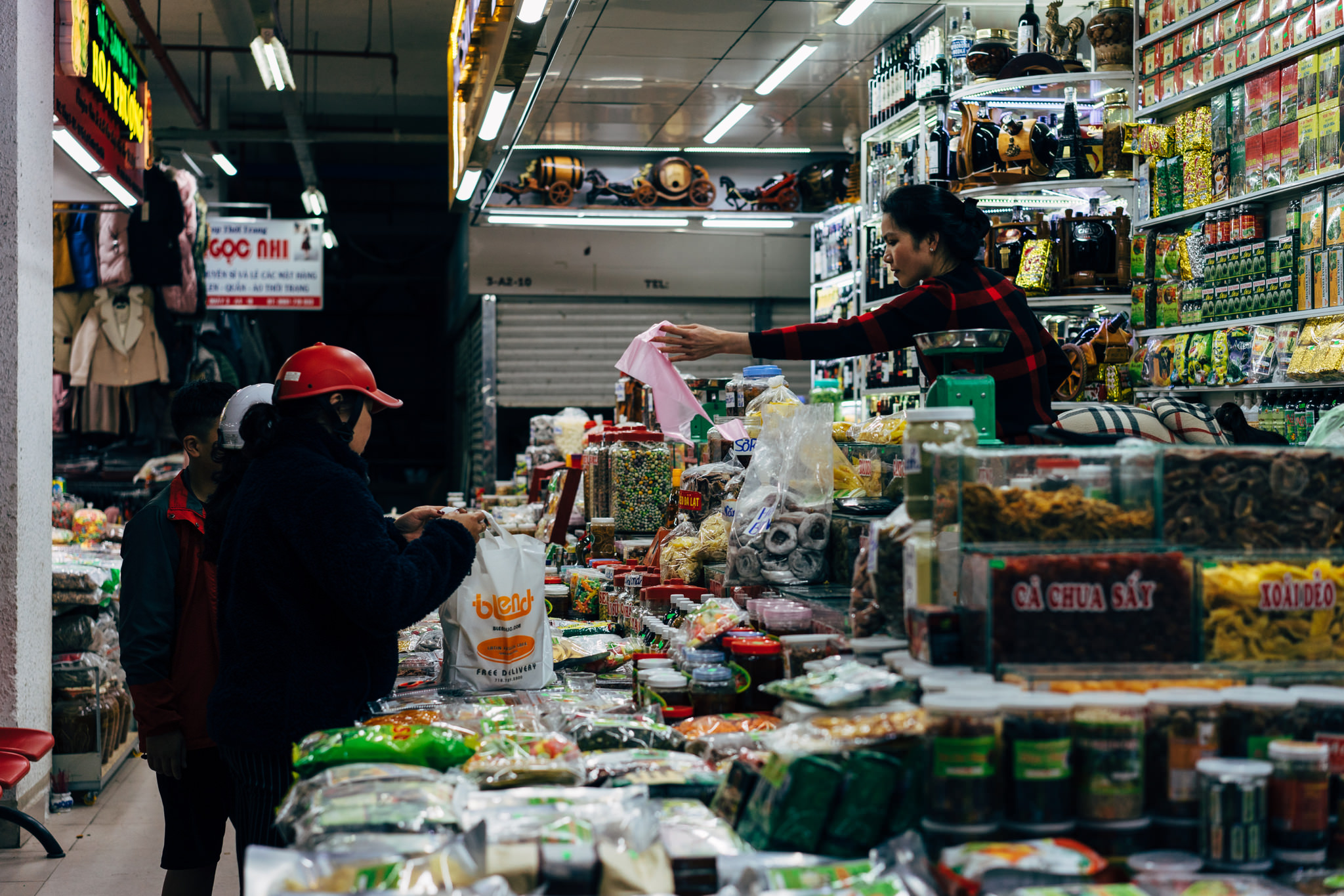 Woman shopping for dried goods at a bustling market.