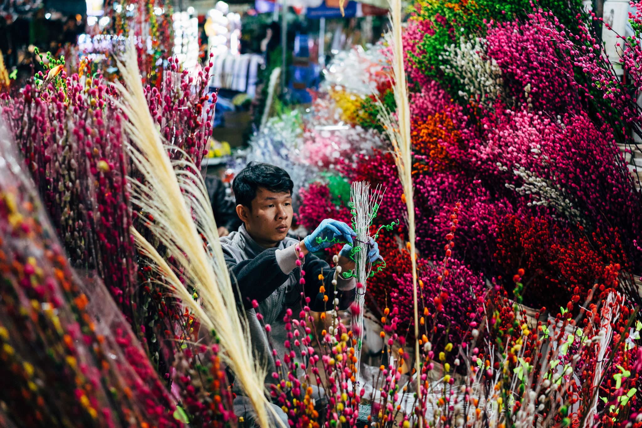 A person arranging colorful flowers at a night market in Da Lat, Vietnam.