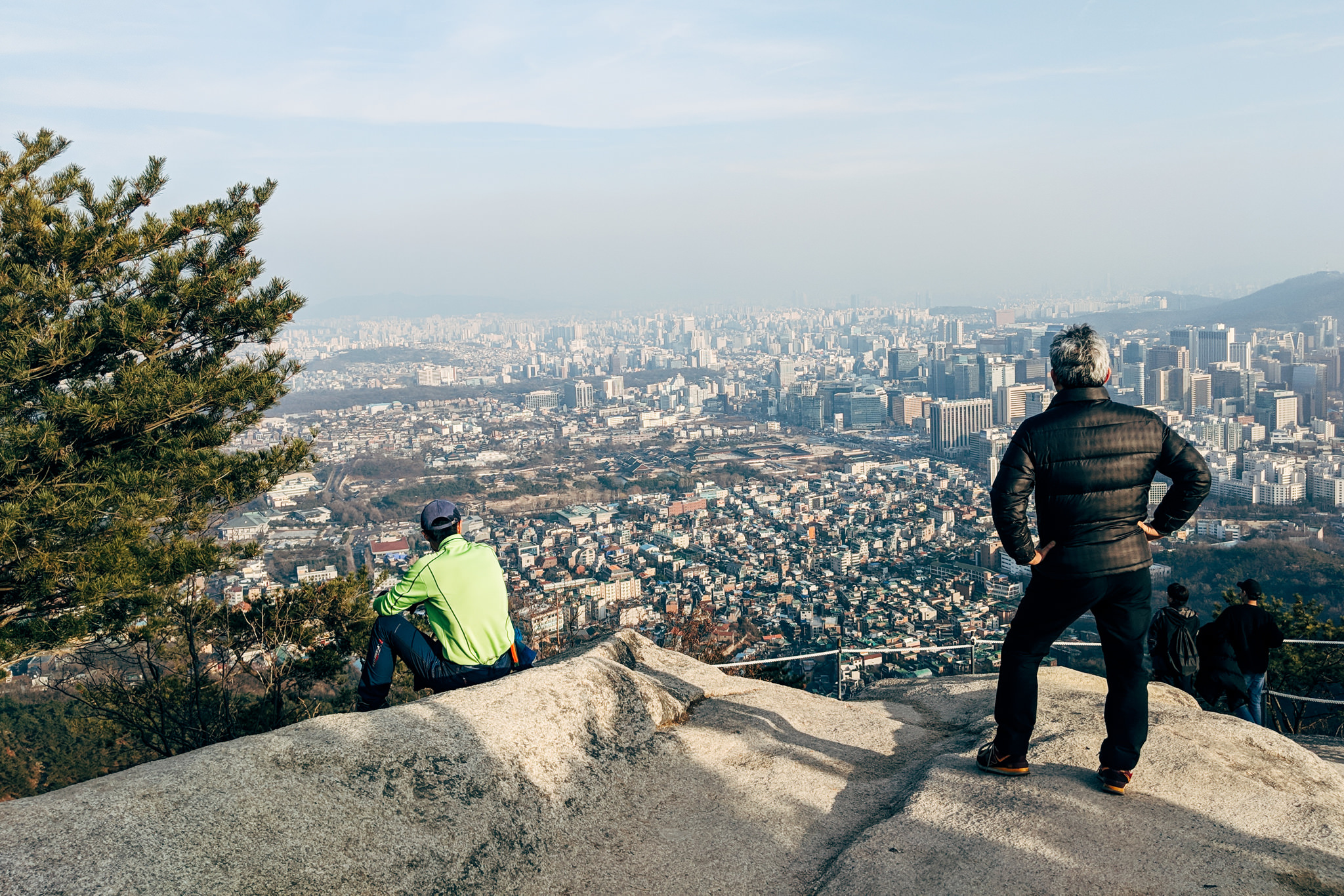 Two people sitting on a rock overlooking Seoul, South Korea.
