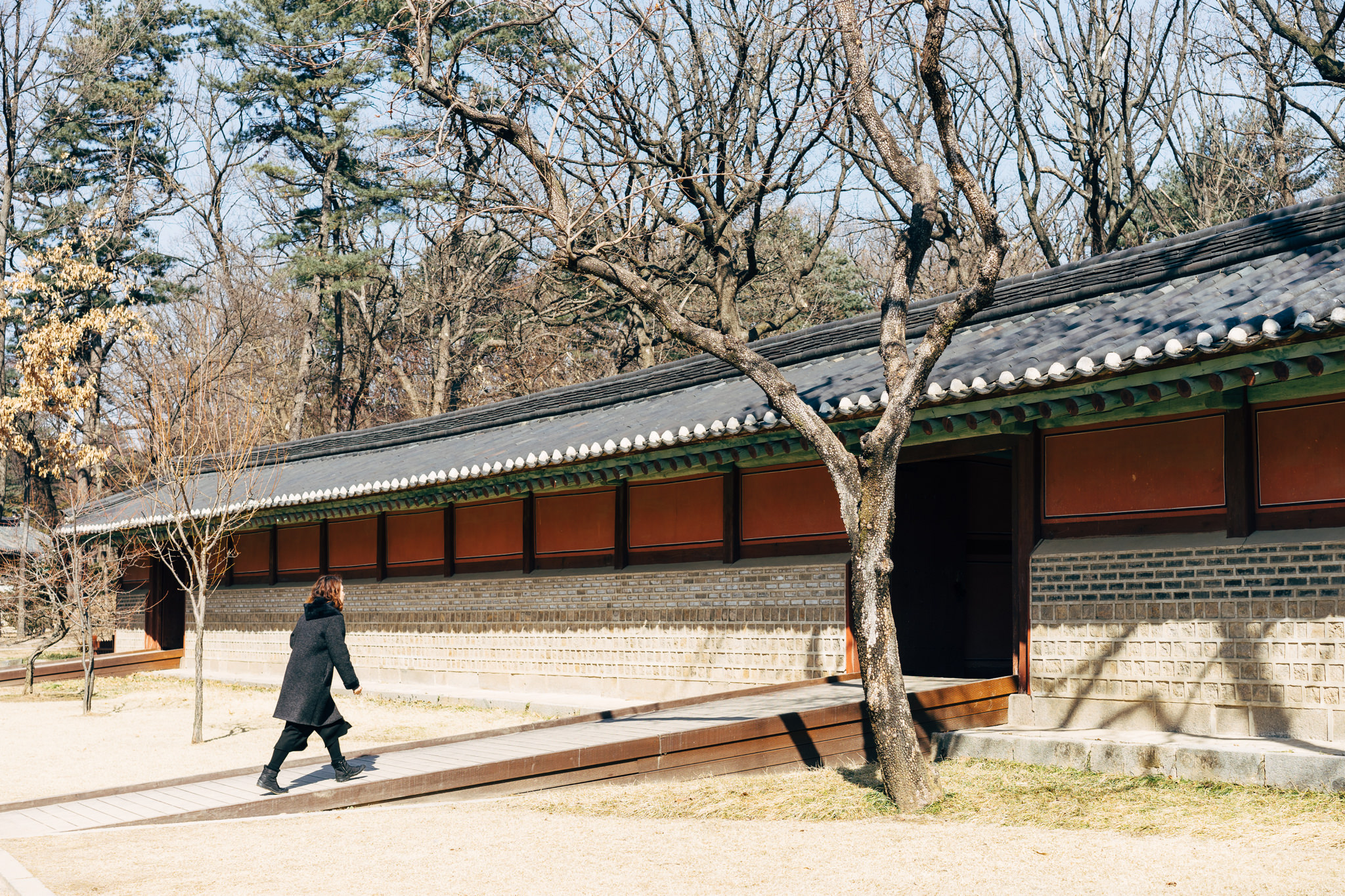 Person walking on a path near a traditional Korean building.