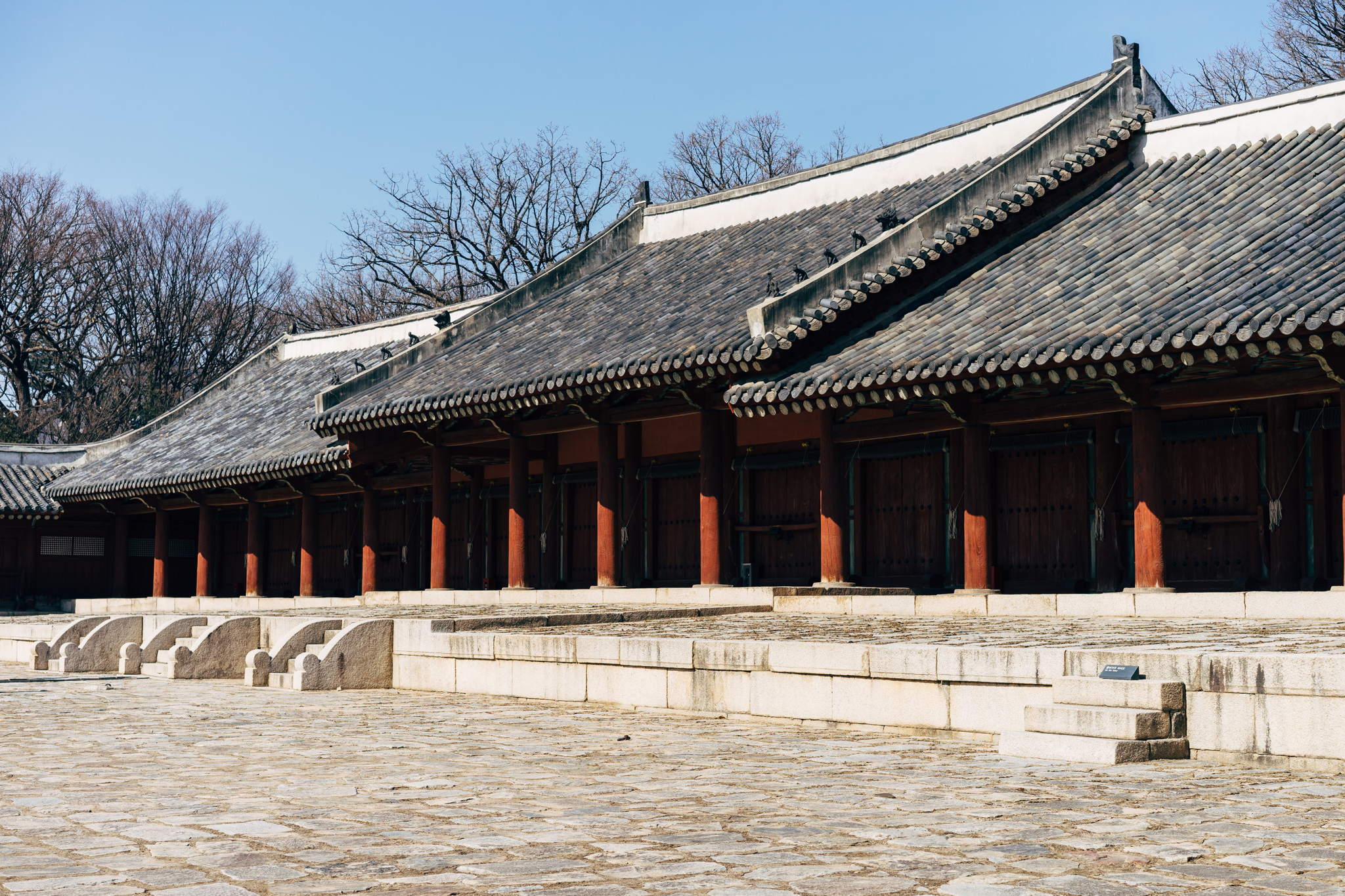 Jongmyo Shrine in Seoul, long low building with grey tiled roof and red columns.