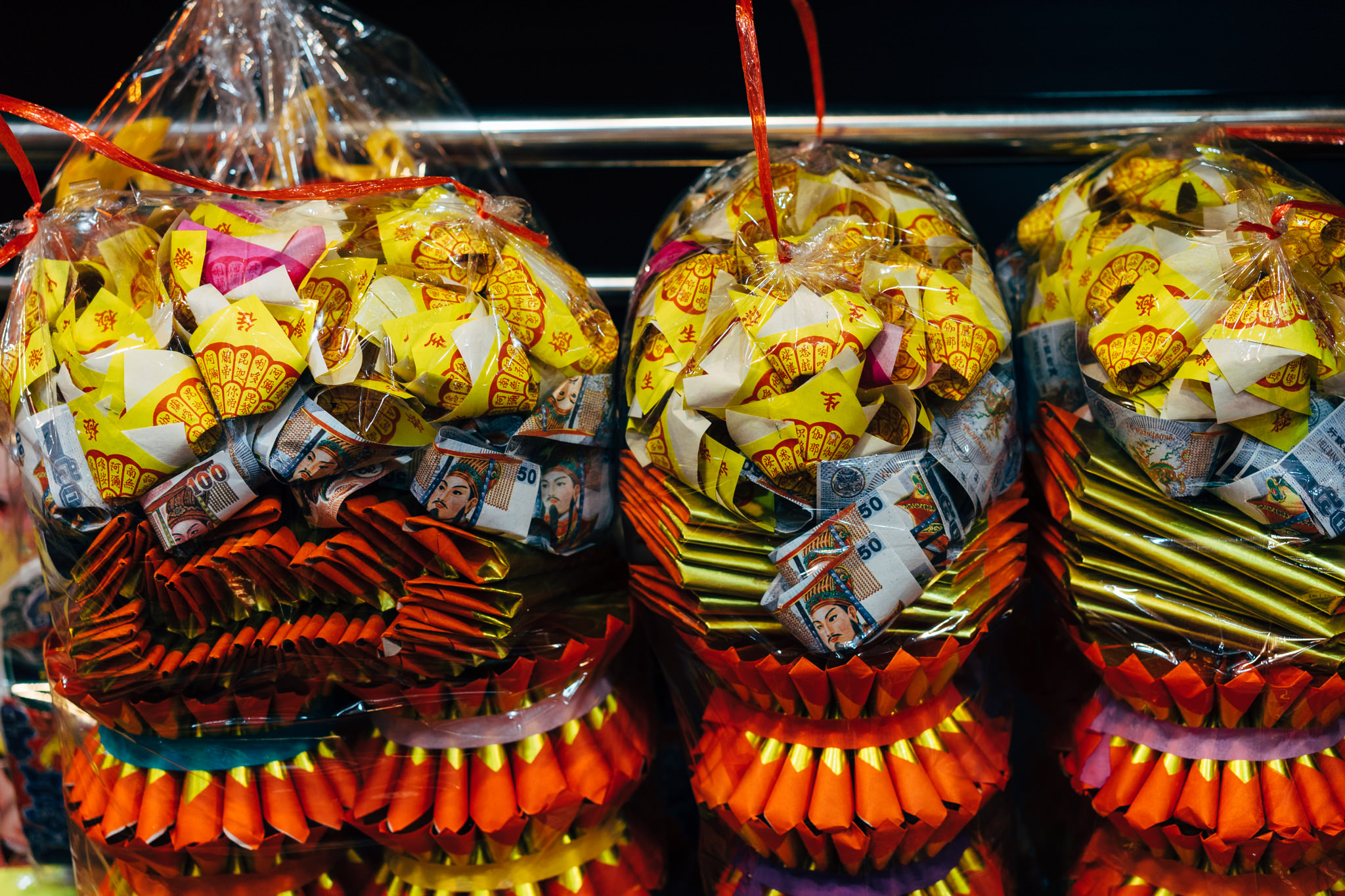 Three plastic bags of joss paper and banknotes for burning at a Bangkok market.