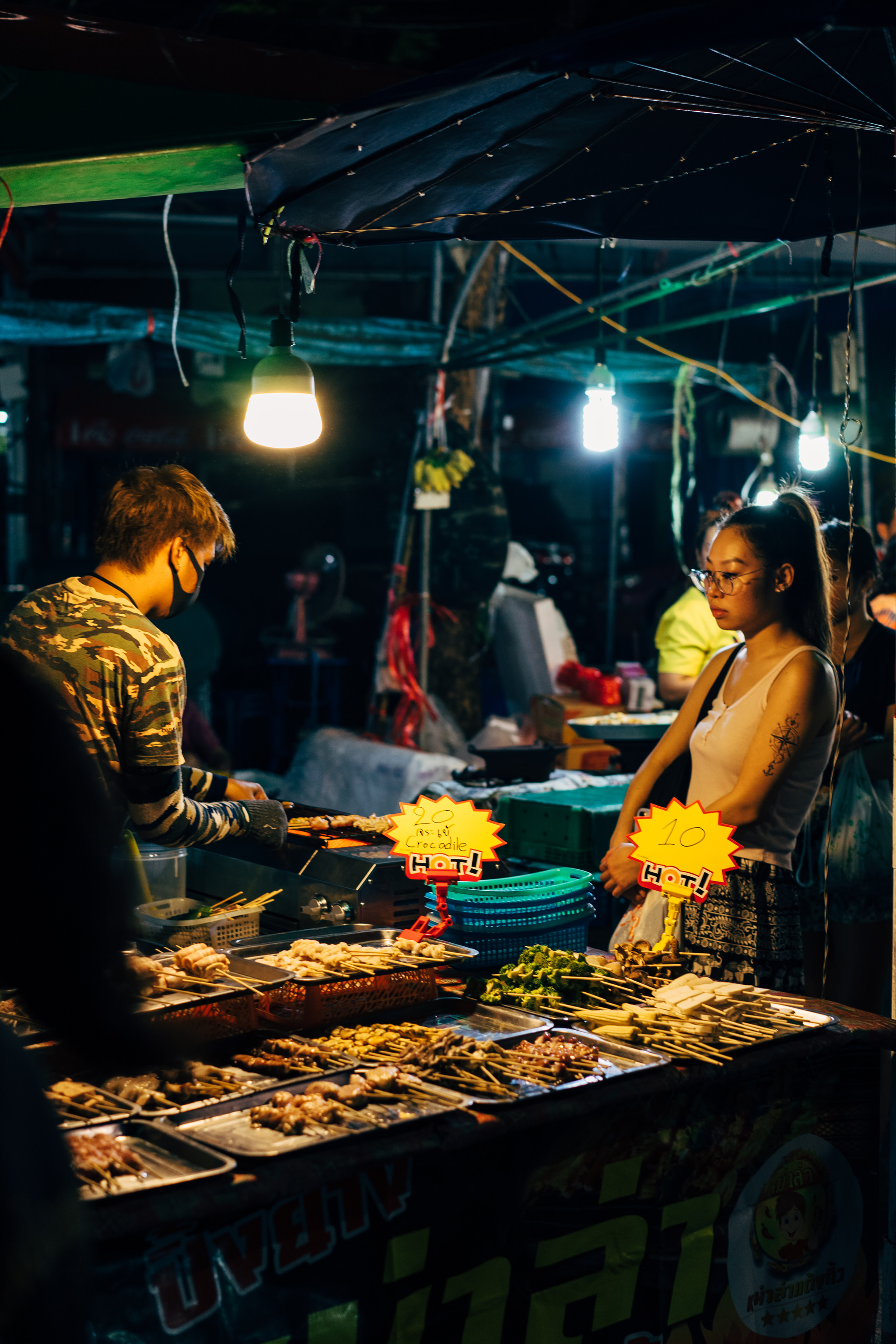 Bangkok night market food stall with grilled skewers.