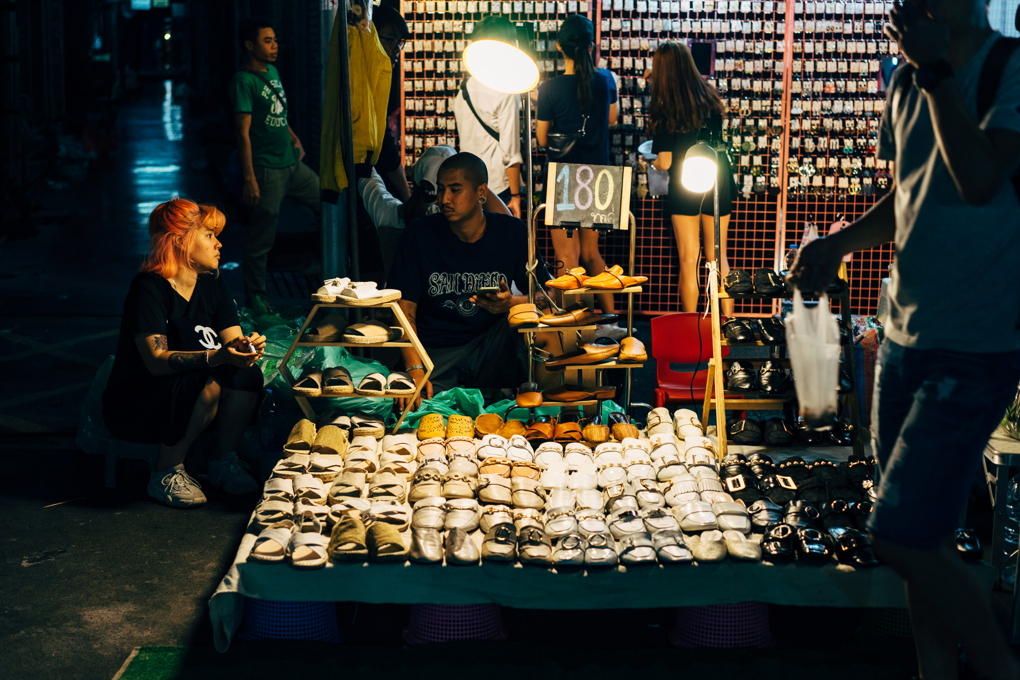 Bangkok night market stall selling many sandals and shoes.
